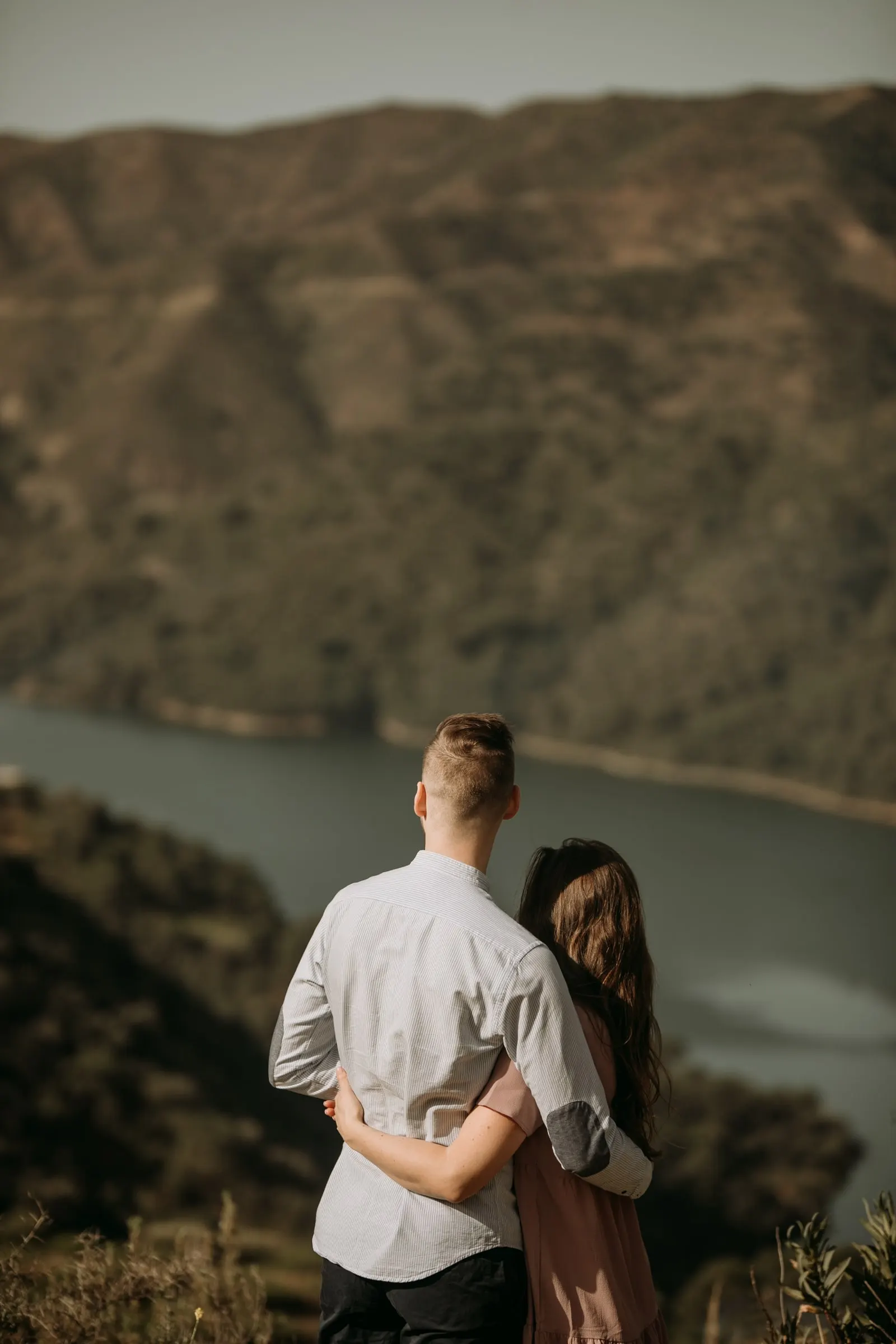 La pareja de espaldas, abrazada sobre el valle del embalse