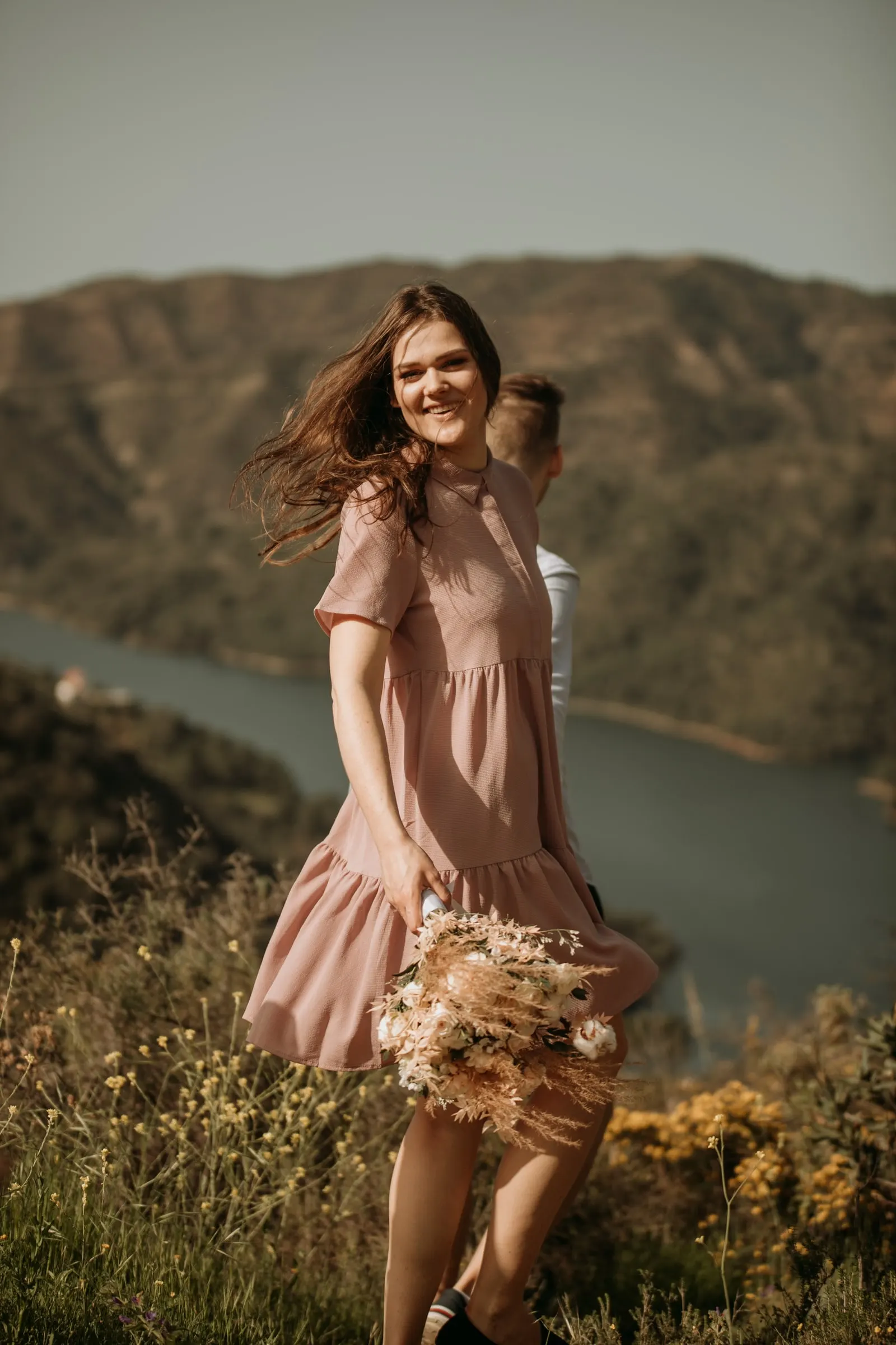 La futura novia gira con su vestido rosa y el pelo al viento, con el embalse detrás