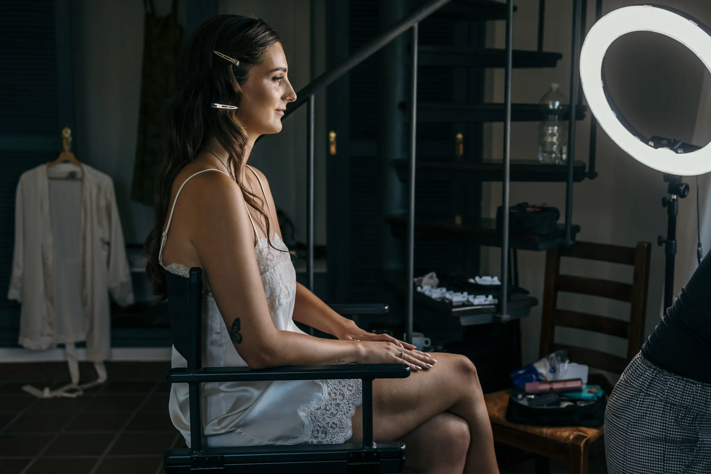 Bride in a director's chair by a spiral staircase, getting ready at a hillside finca on the Costa del Sol