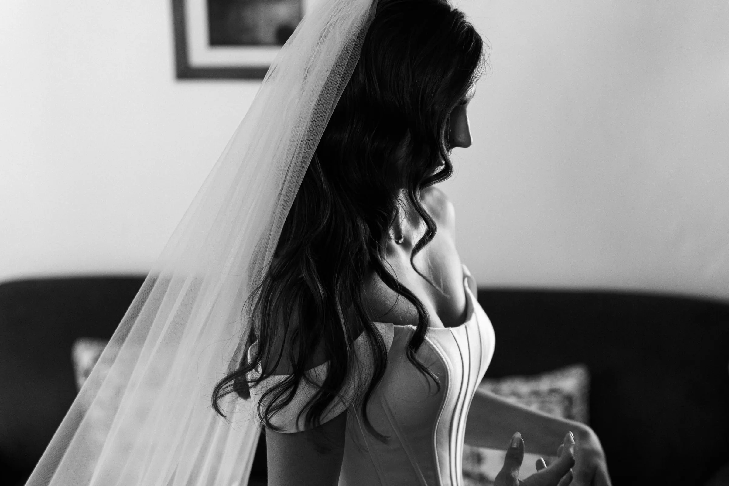 Black and white profile of the bride in her long veil, dark wavy hair over her shoulders