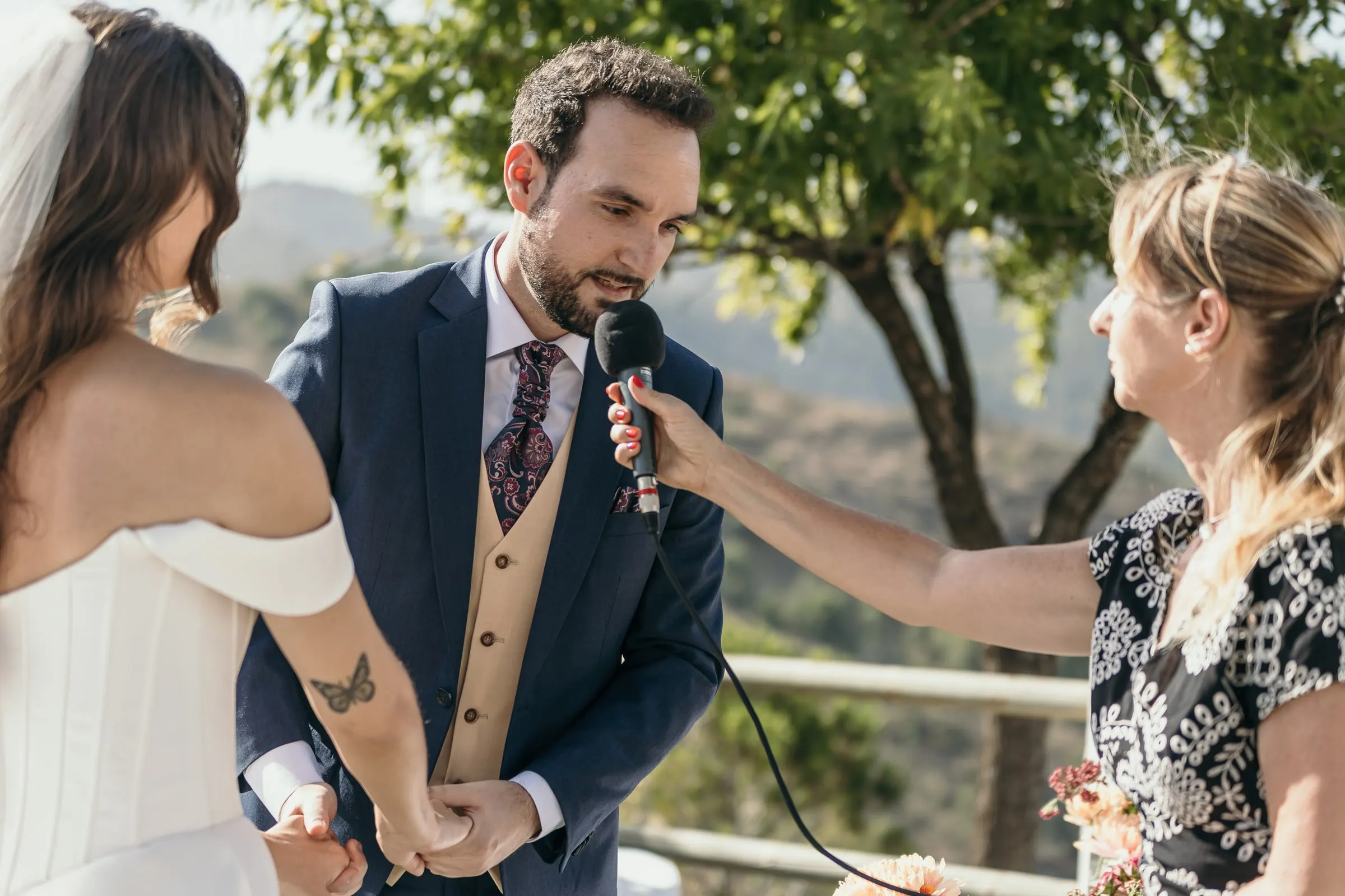 Groom saying his vows into a microphone held by the celebrant