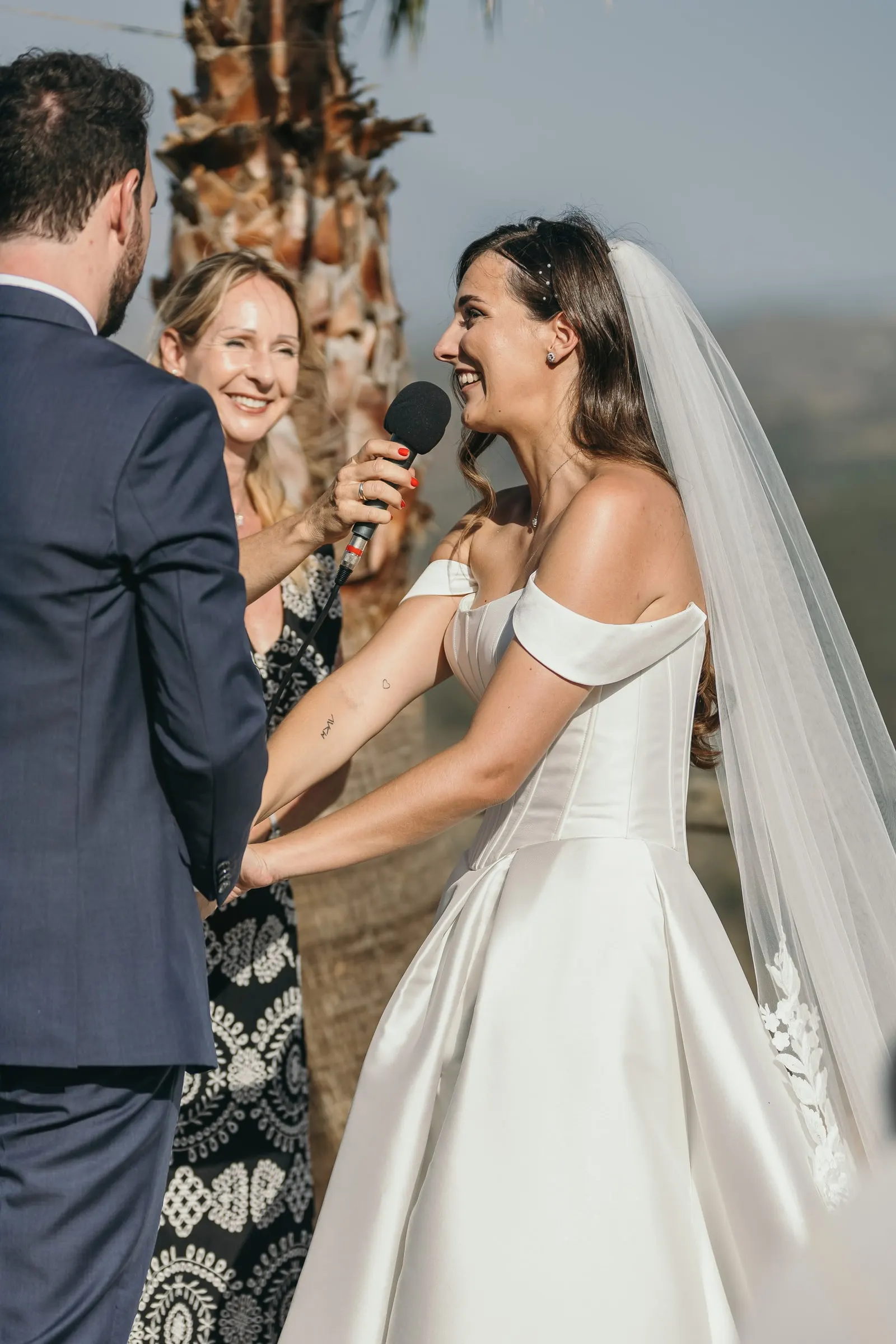 Bride laughing as she says her vows into the microphone