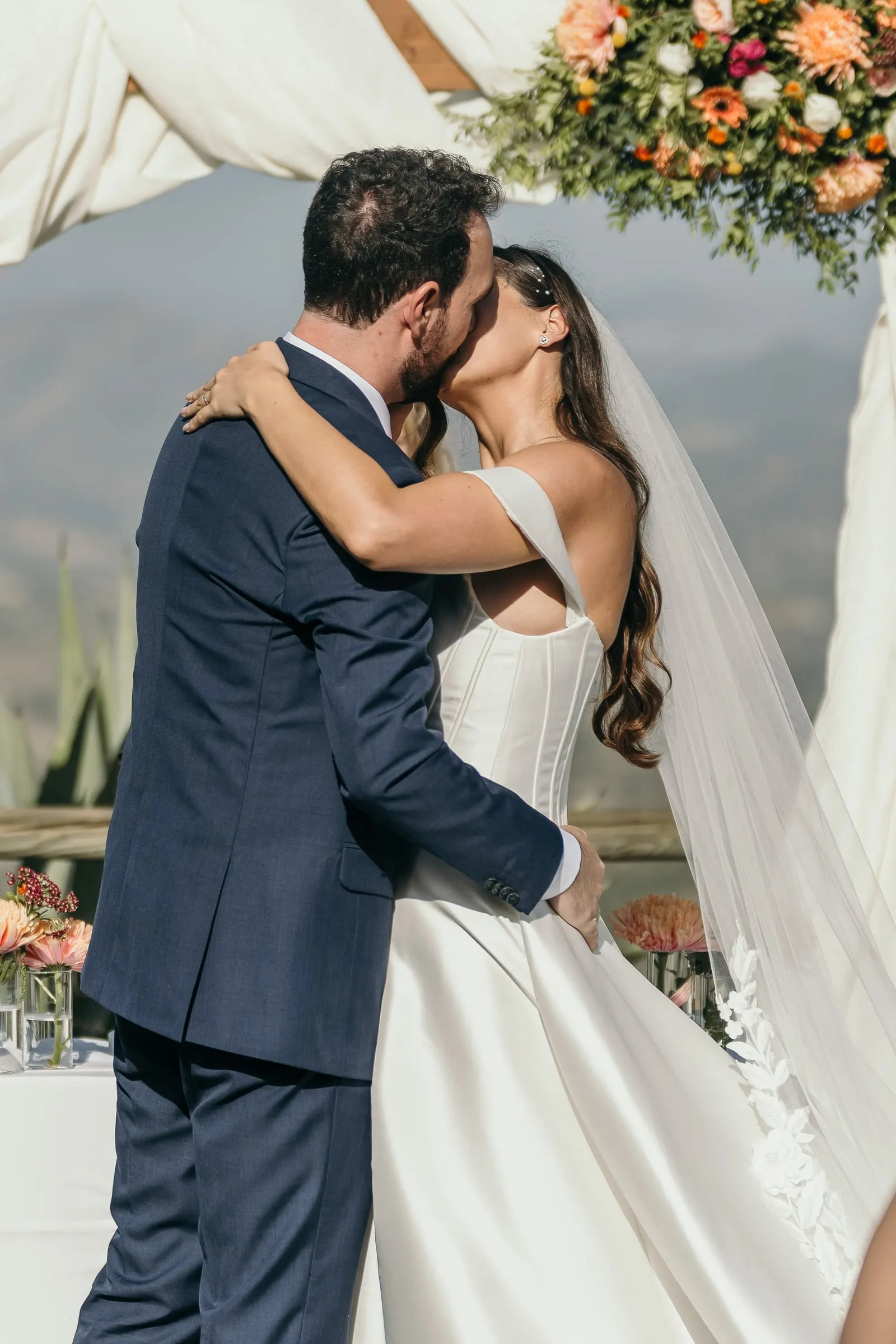 First kiss under the floral arch with the mountains of the Costa del Sol behind