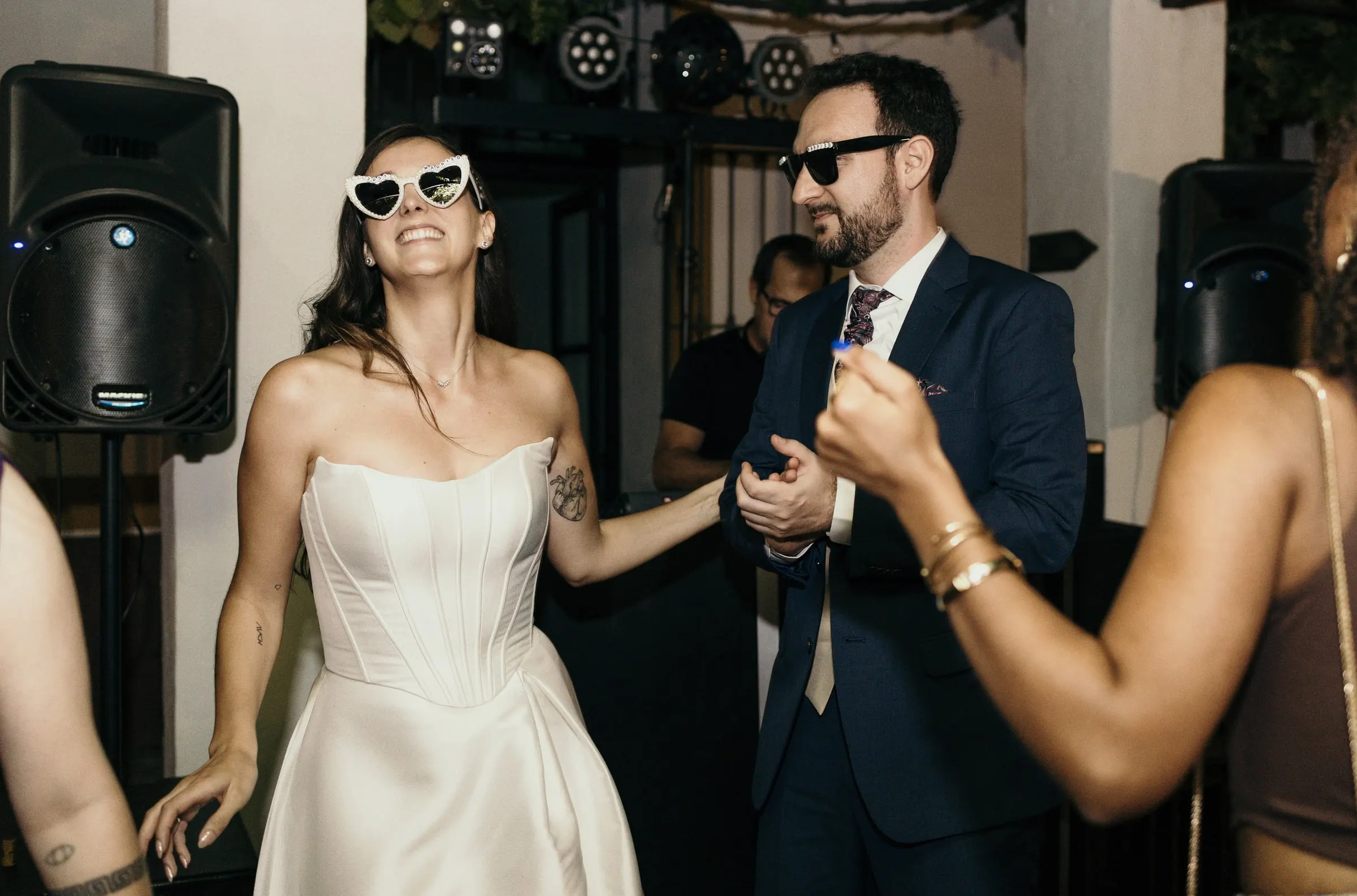 Bride in heart-shaped sunglasses dancing with the groom in dark glasses