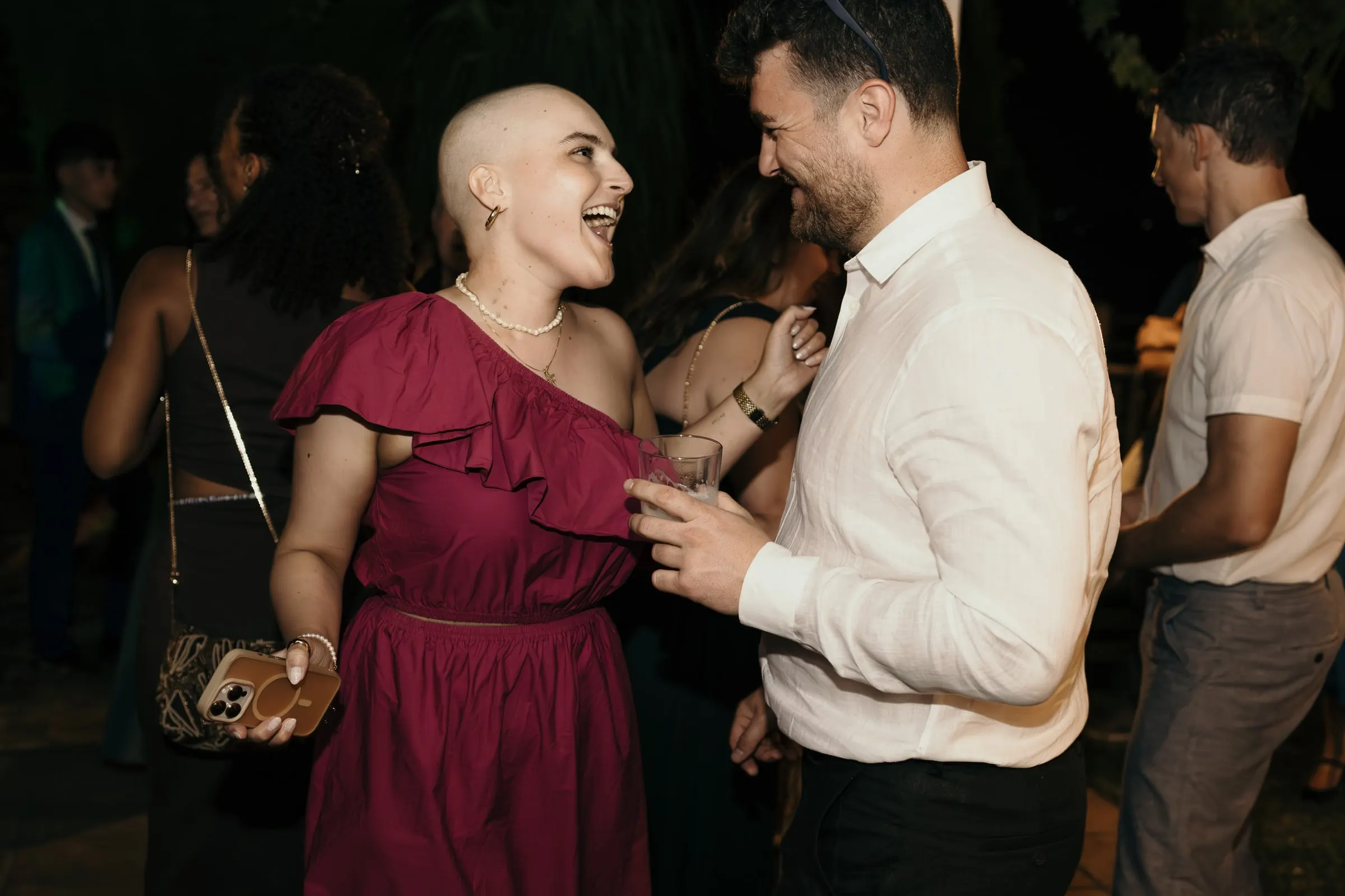 Friend in a magenta dress laughing with a guest on the dance floor