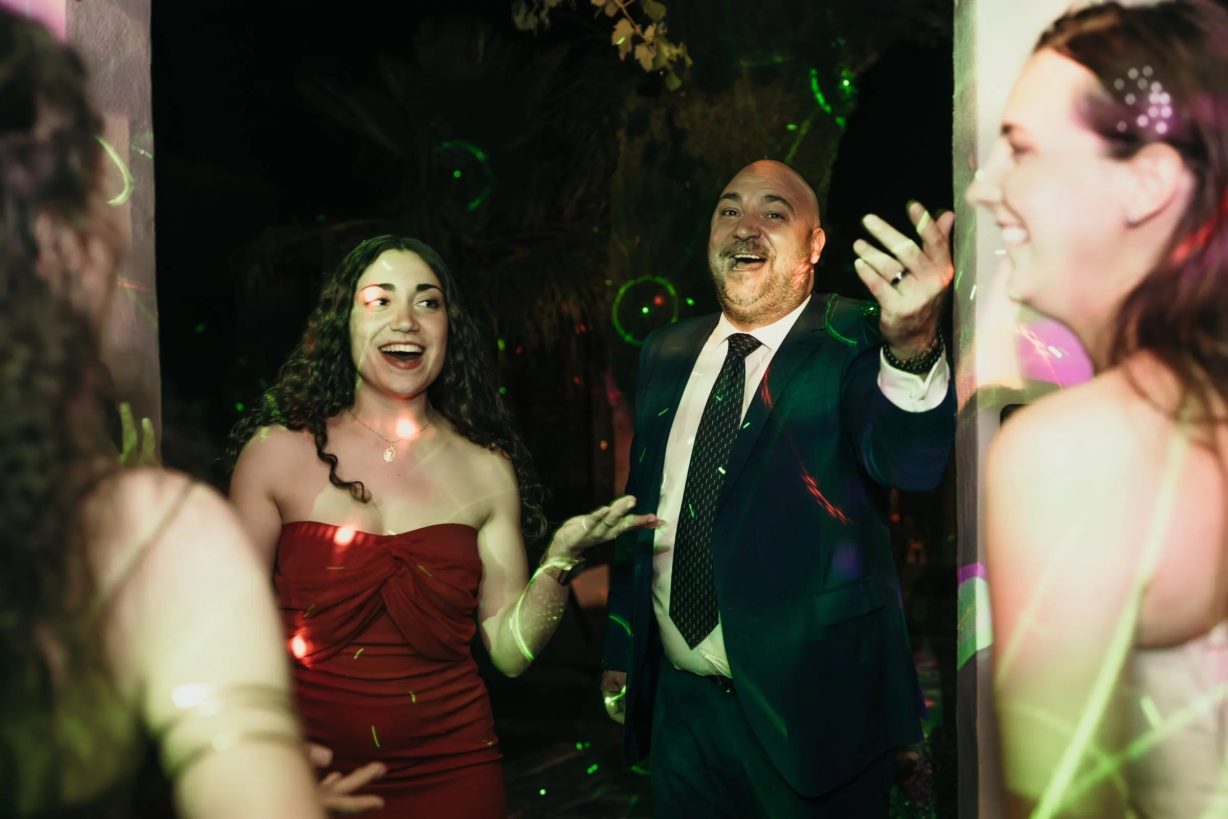 Guests dancing under green laser lights at the wedding party