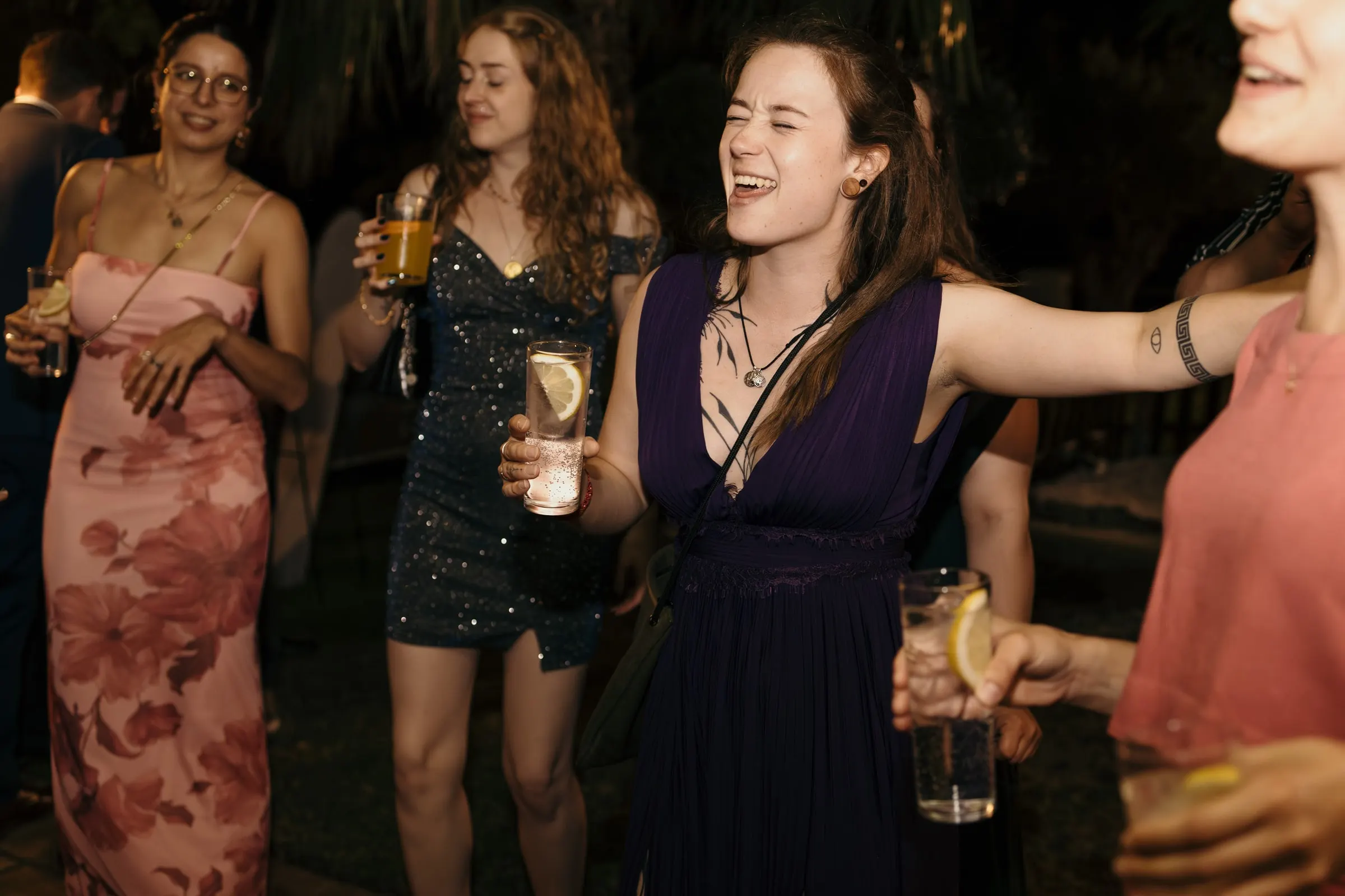 Friends singing and dancing with drinks in hand late at night