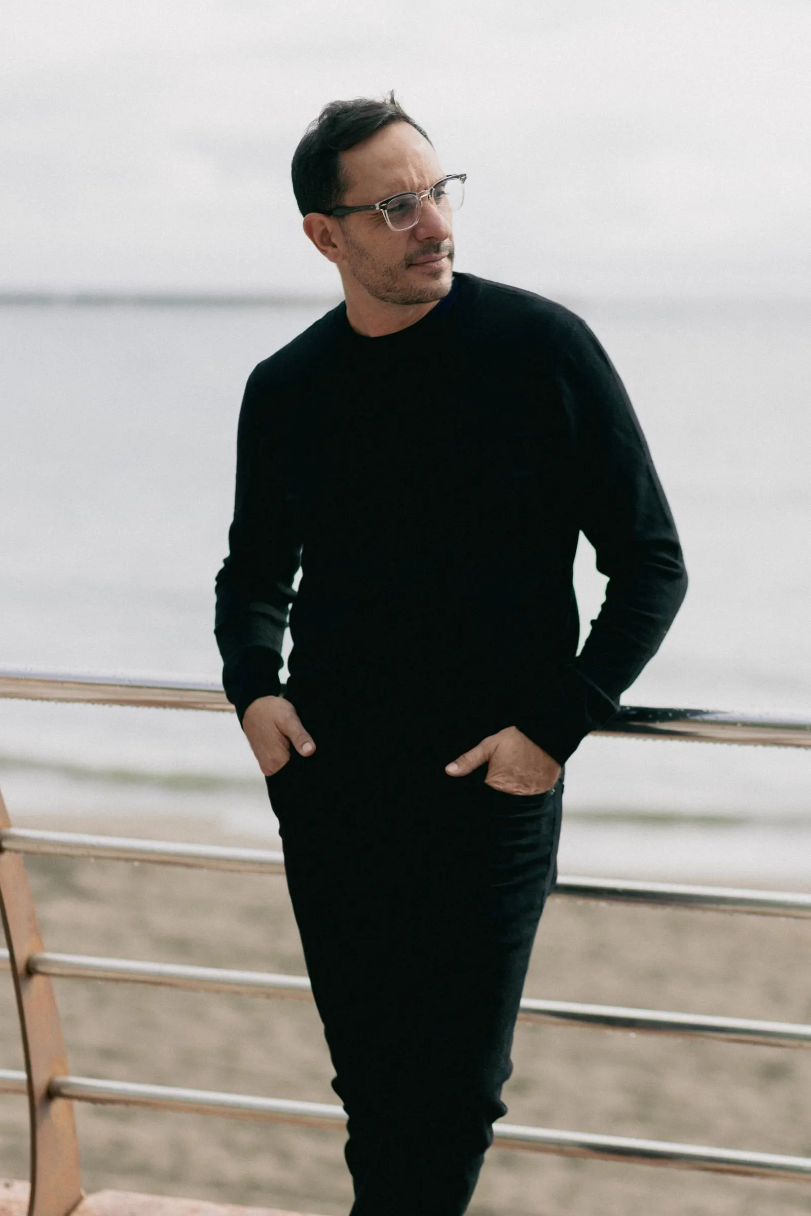 Diego, Picart's photographer, in a black jumper leaning on a seafront railing, Estepona