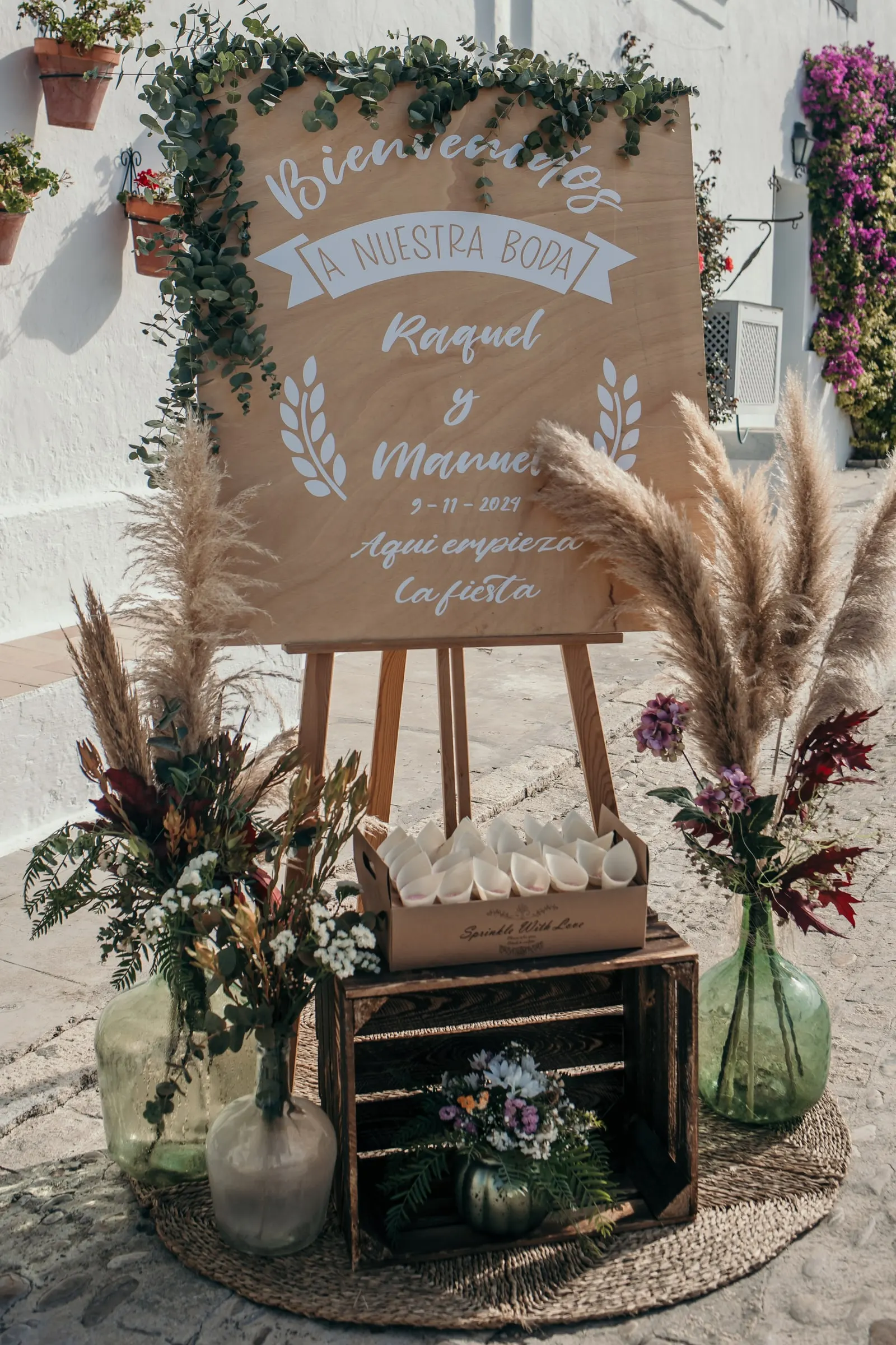 Wooden welcome sign for Raquel and Manuel's wedding with eucalyptus, pampas grass and dried flowers in the cortijo courtyard