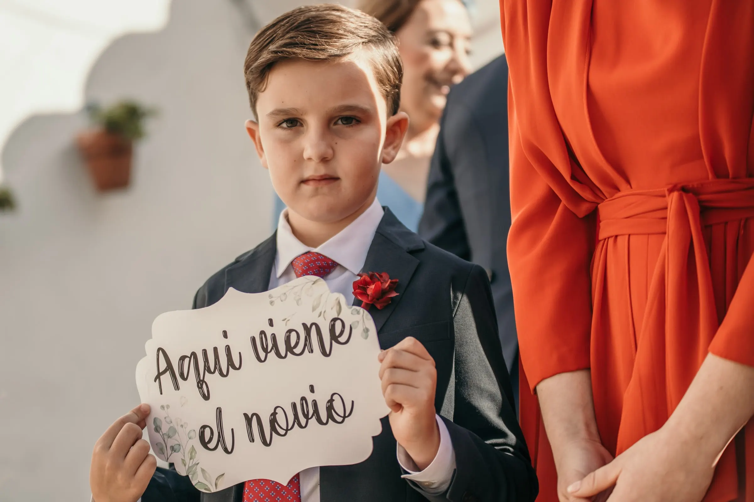 Page boy holding a hand-lettered sign announcing the groom at an Andalusian cortijo wedding