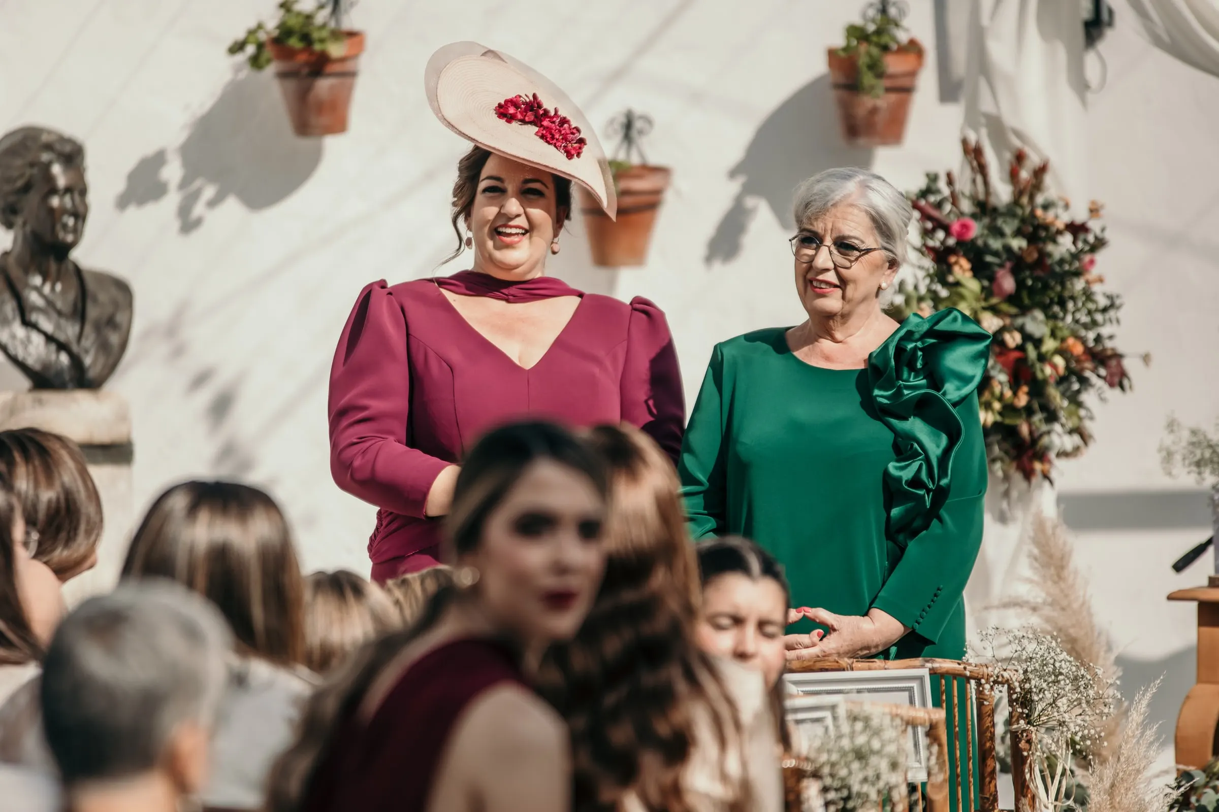 Wedding guests in a fascinator and a green ruffled dress watching the ceremony in the cortijo courtyard