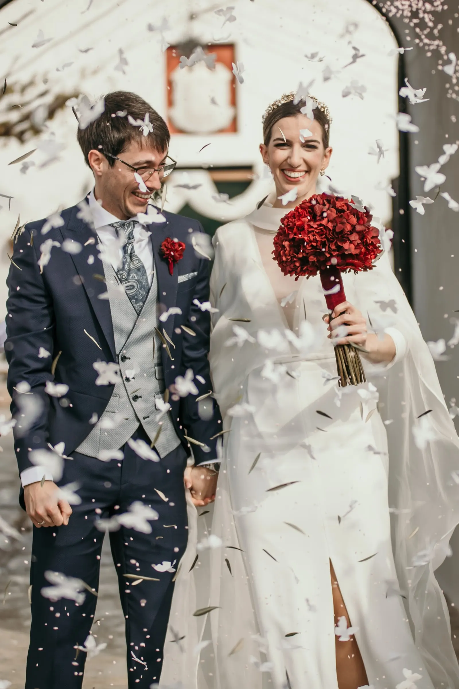 Bride and groom laughing under falling paper confetti outside the cortijo archway