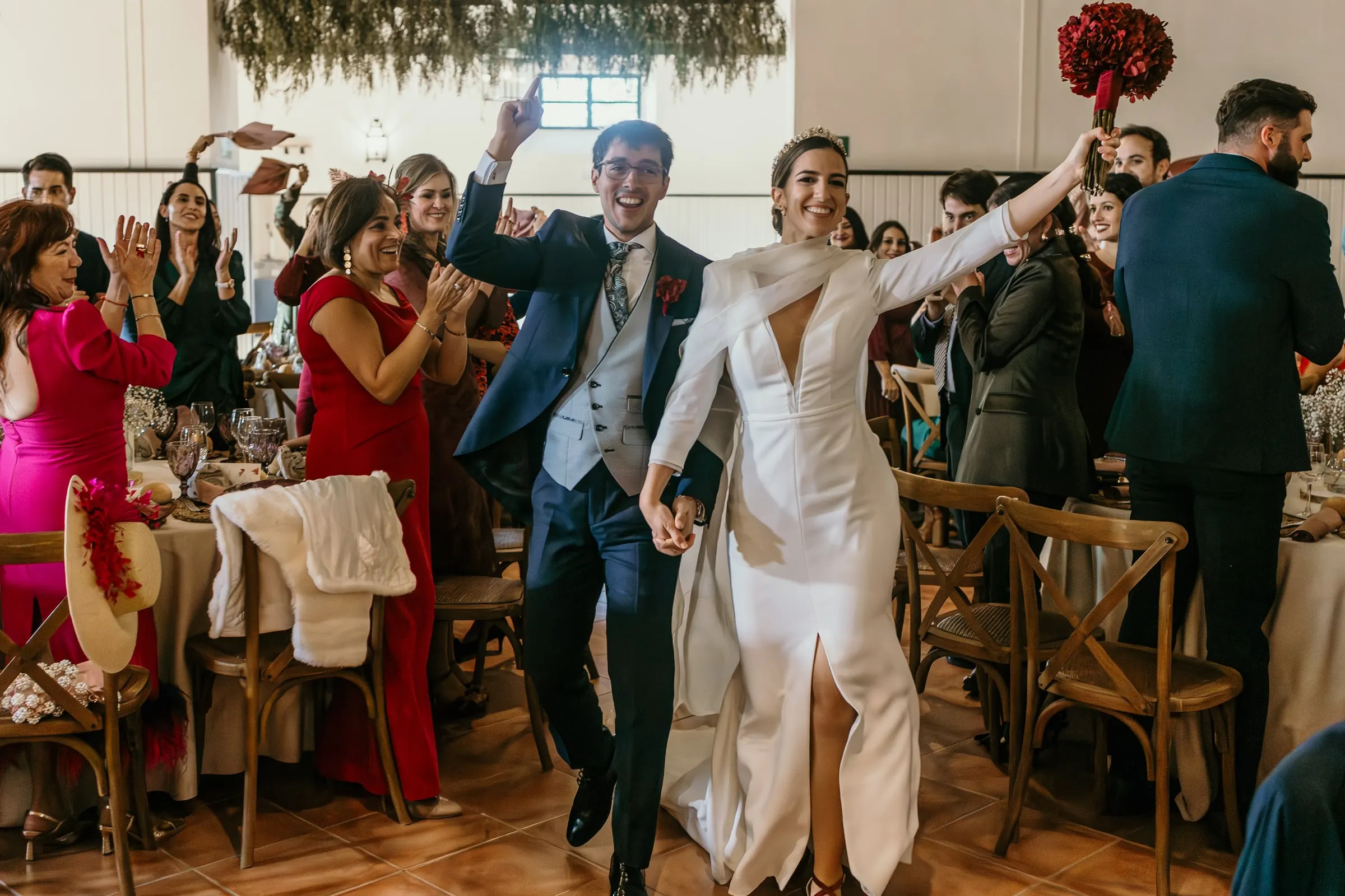 Newlyweds dancing into the banquet hall to applause from guests at their tables