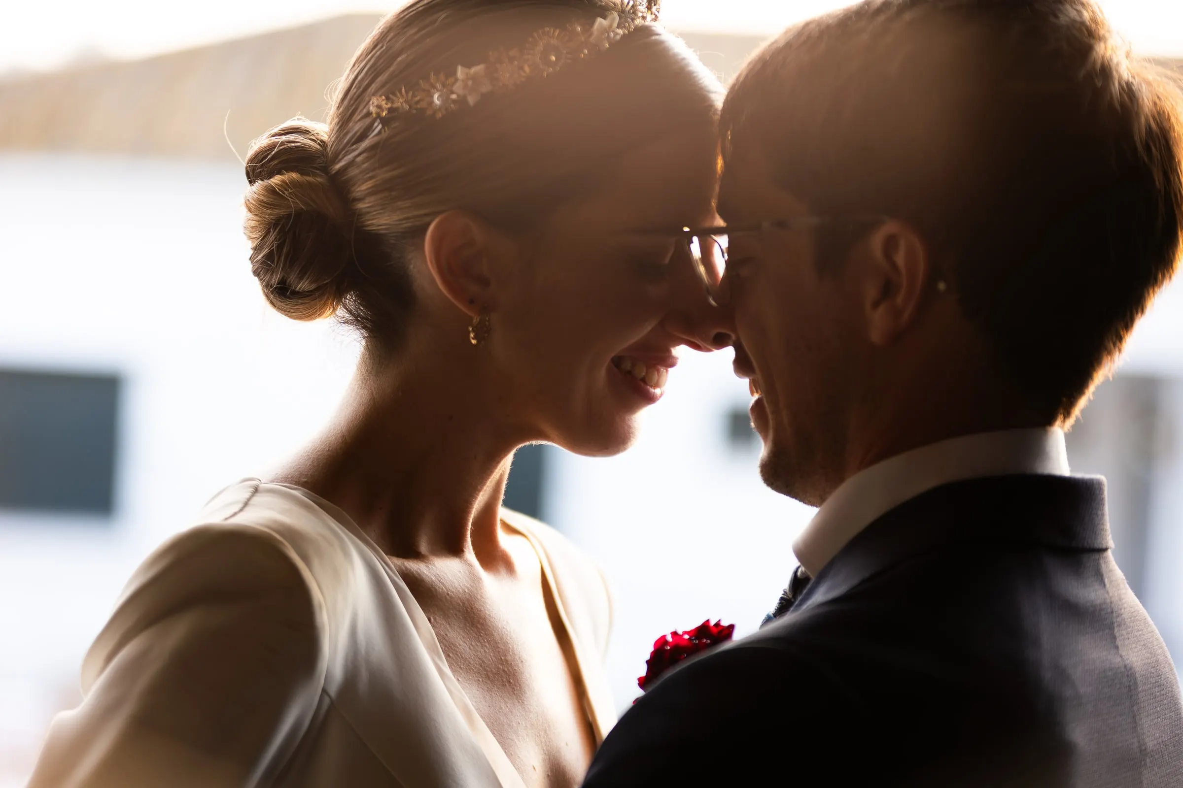 Bride and groom forehead to forehead in golden backlight against the whitewashed walls