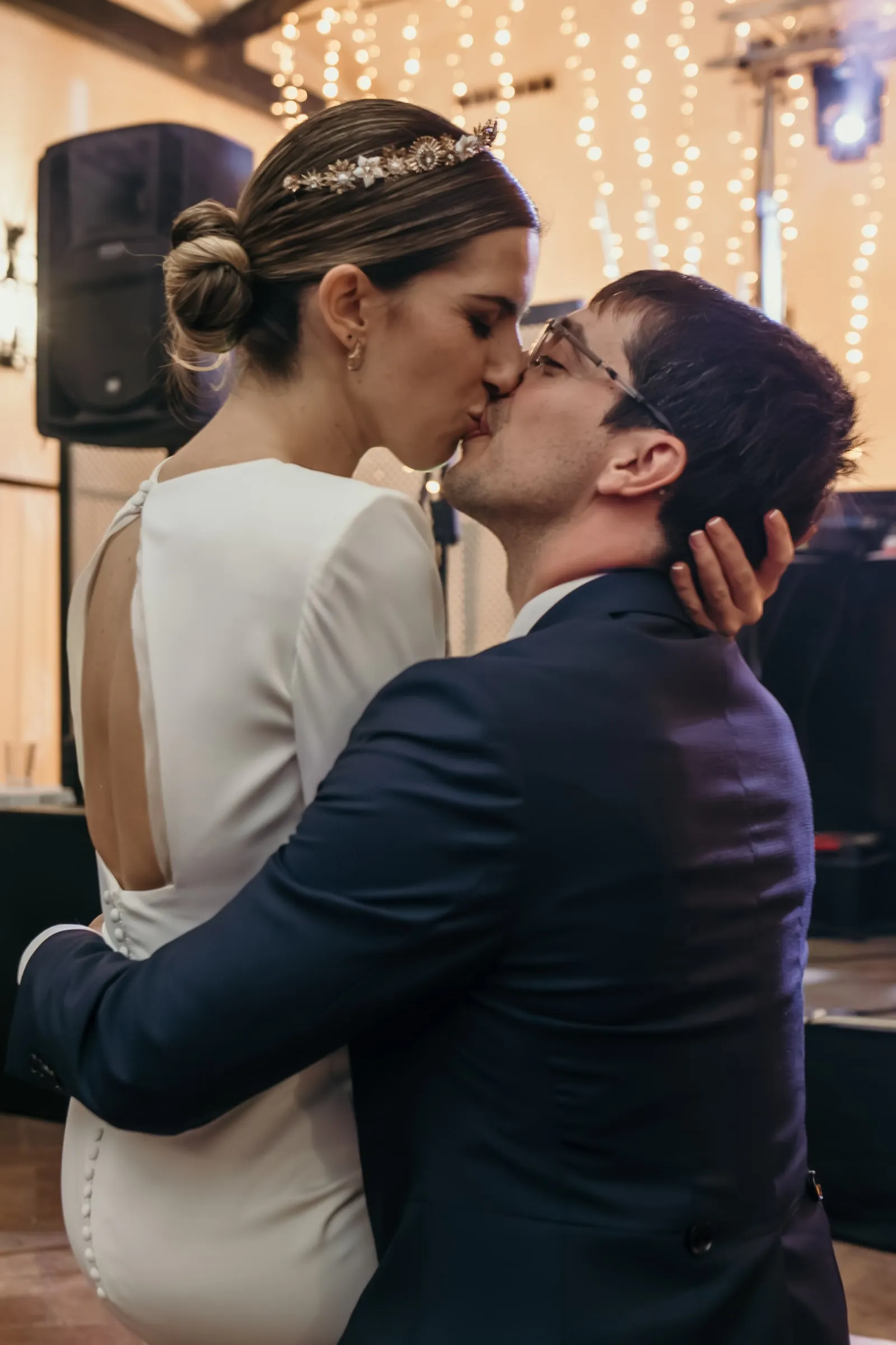 Bride and groom kissing on the dance floor under curtains of fairy lights