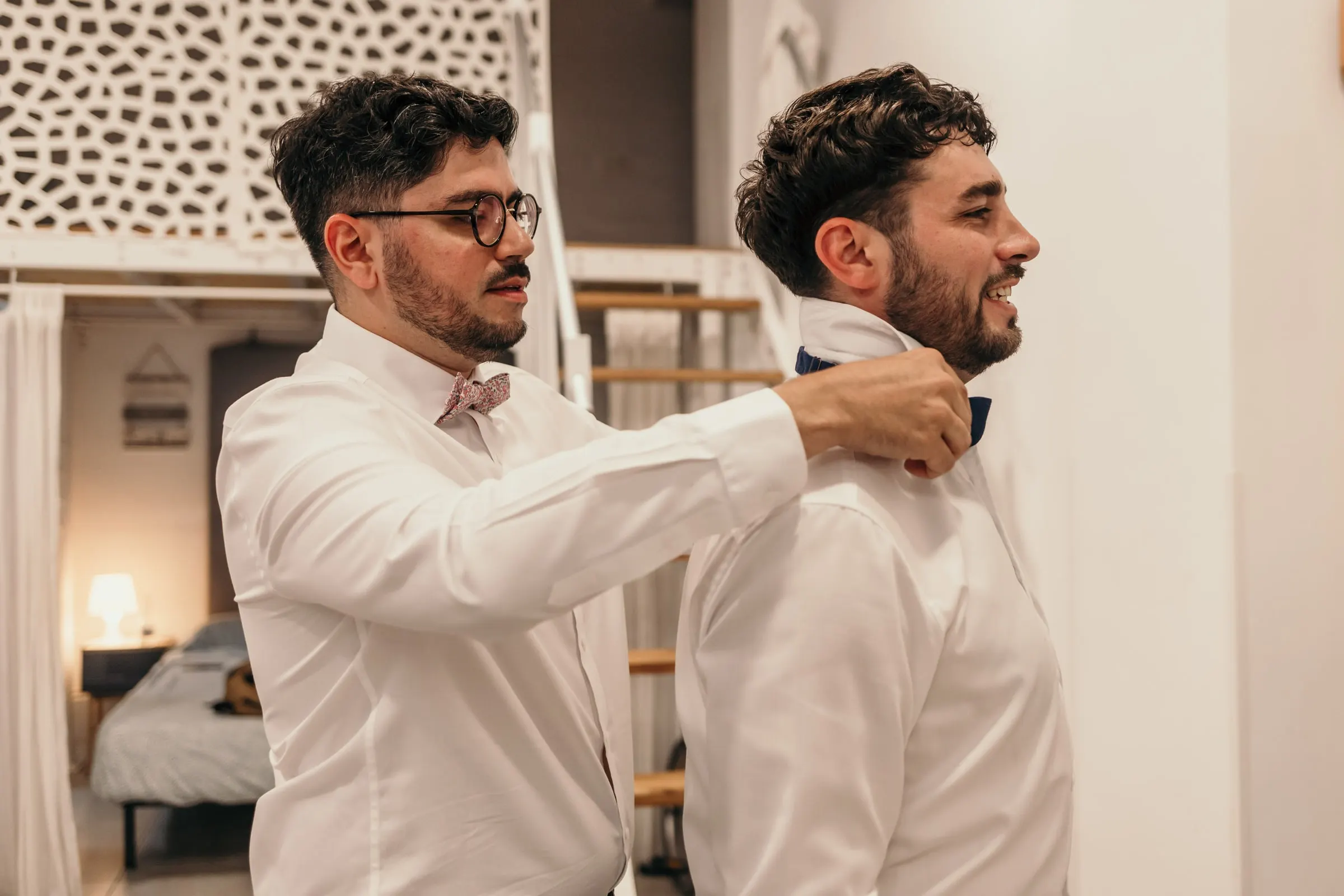 Friend fastening the groom's bow tie in a bright bedroom before the wedding on the Costa del Sol