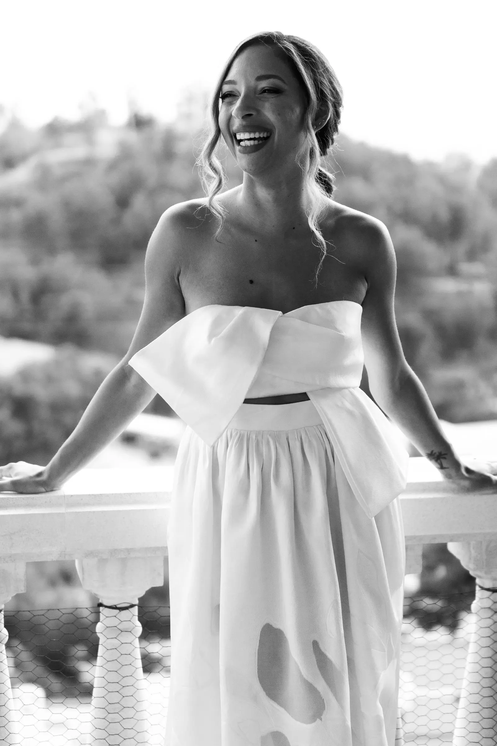 Black and white photo of the bride laughing against the balcony railing