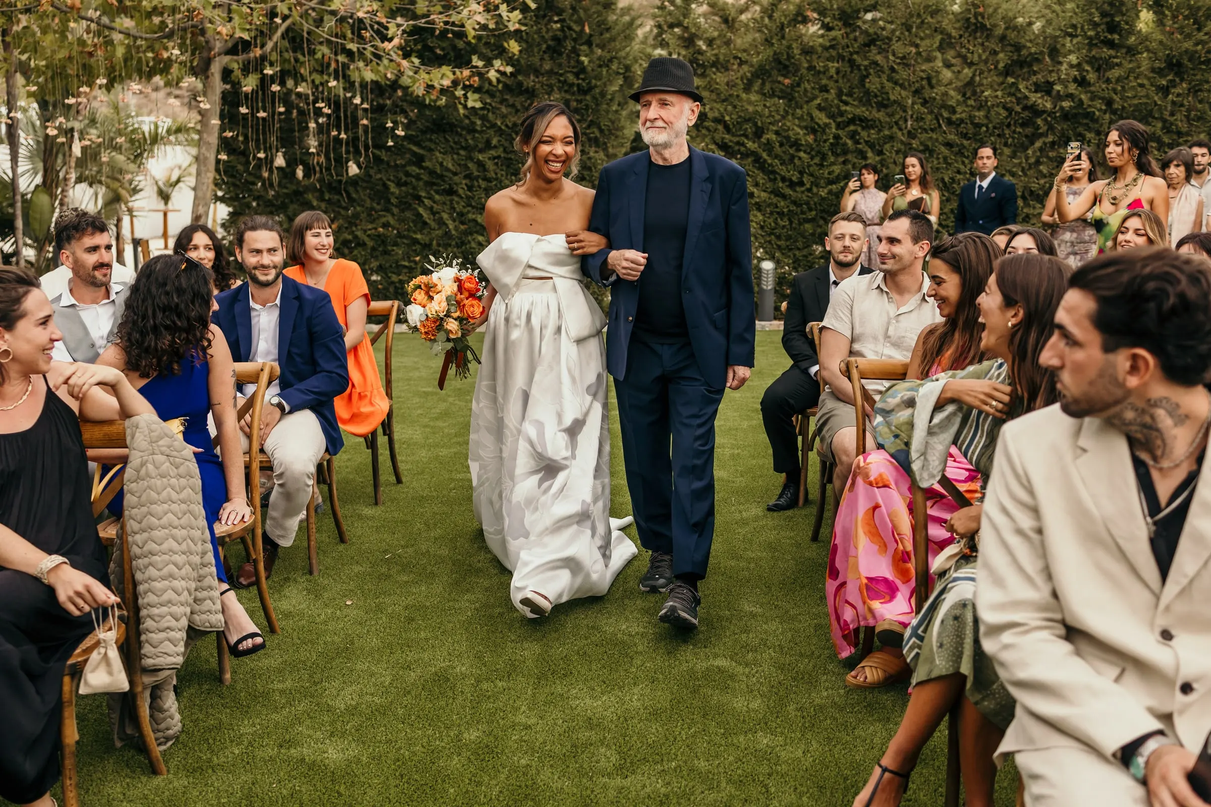 Guests turning in their chairs as the bride walks down the grass aisle on the Costa del Sol