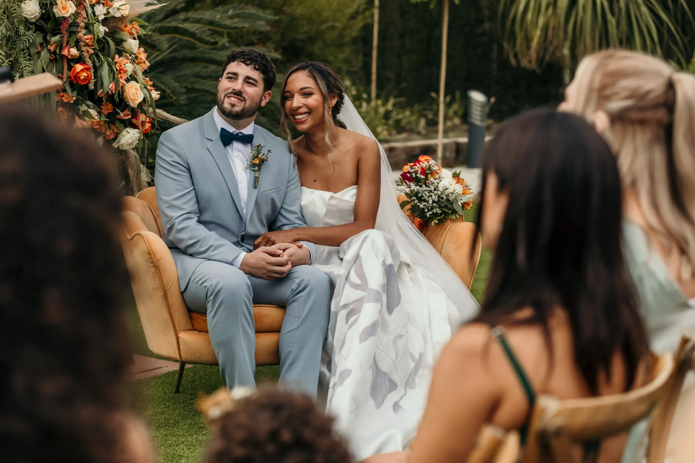 Couple seated at the ceremony seen between two guests in the front row