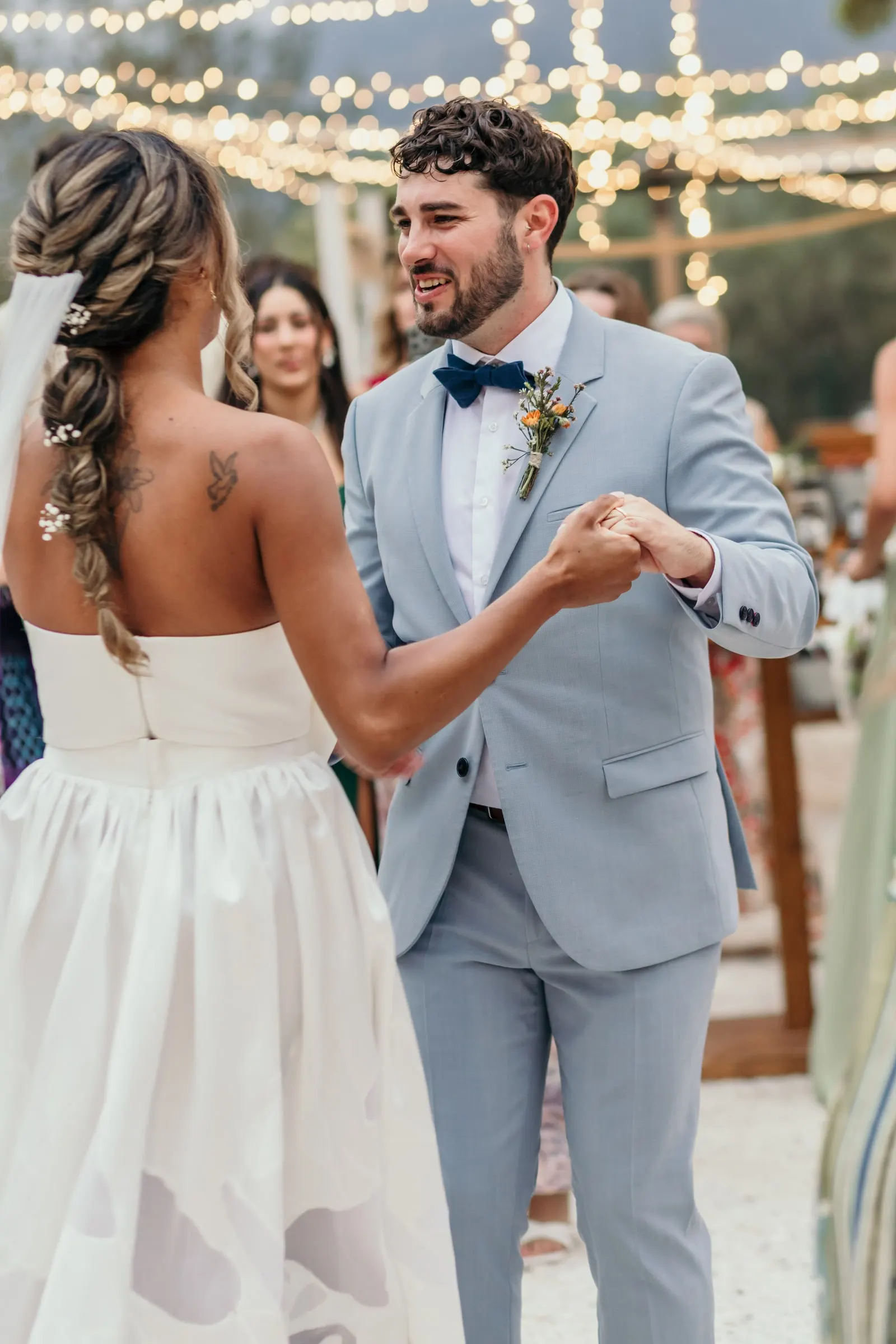 Bride and groom dancing hand in hand under the fairy lights