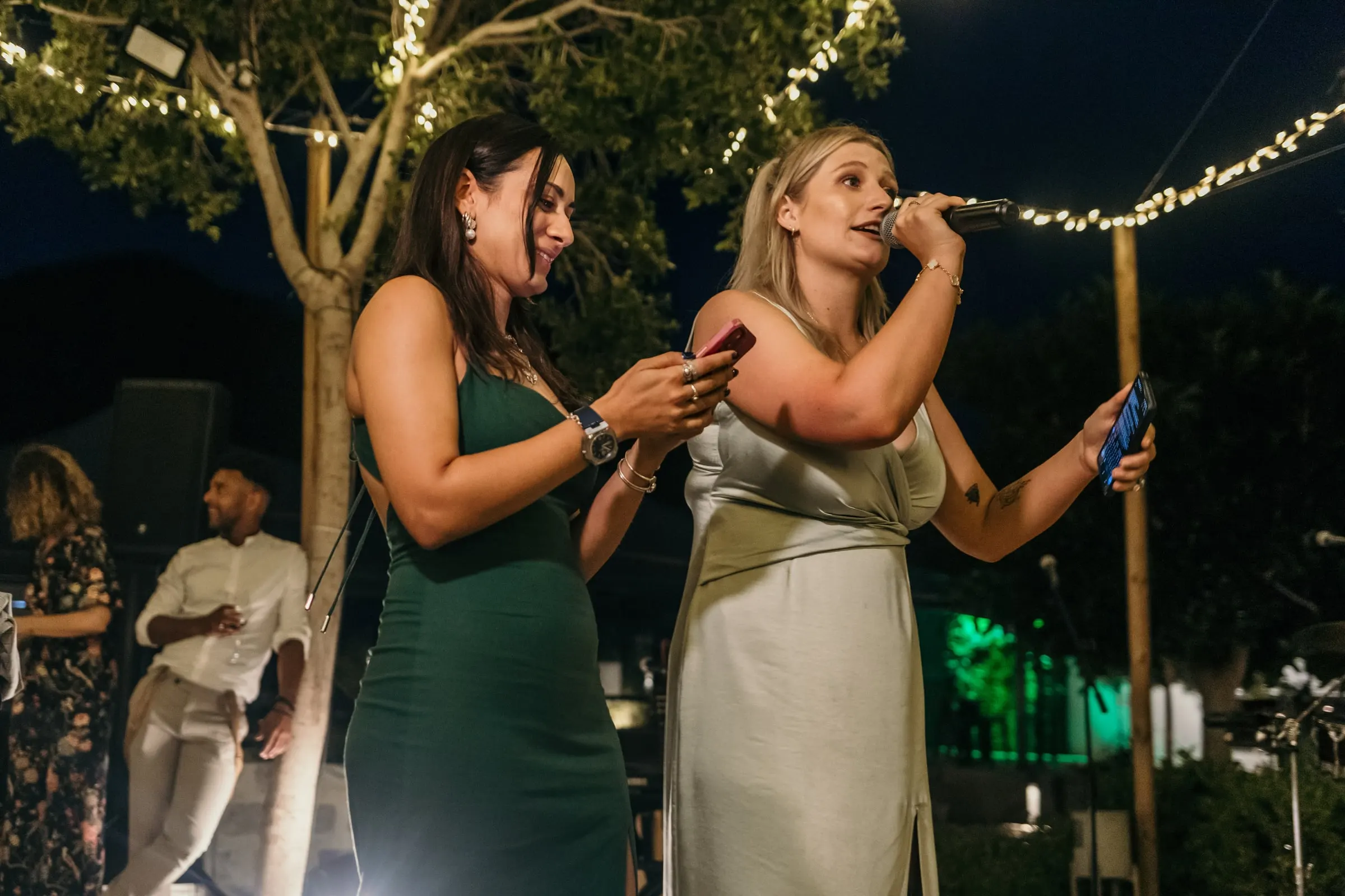 Two bridesmaids reading their speech from their phones at night