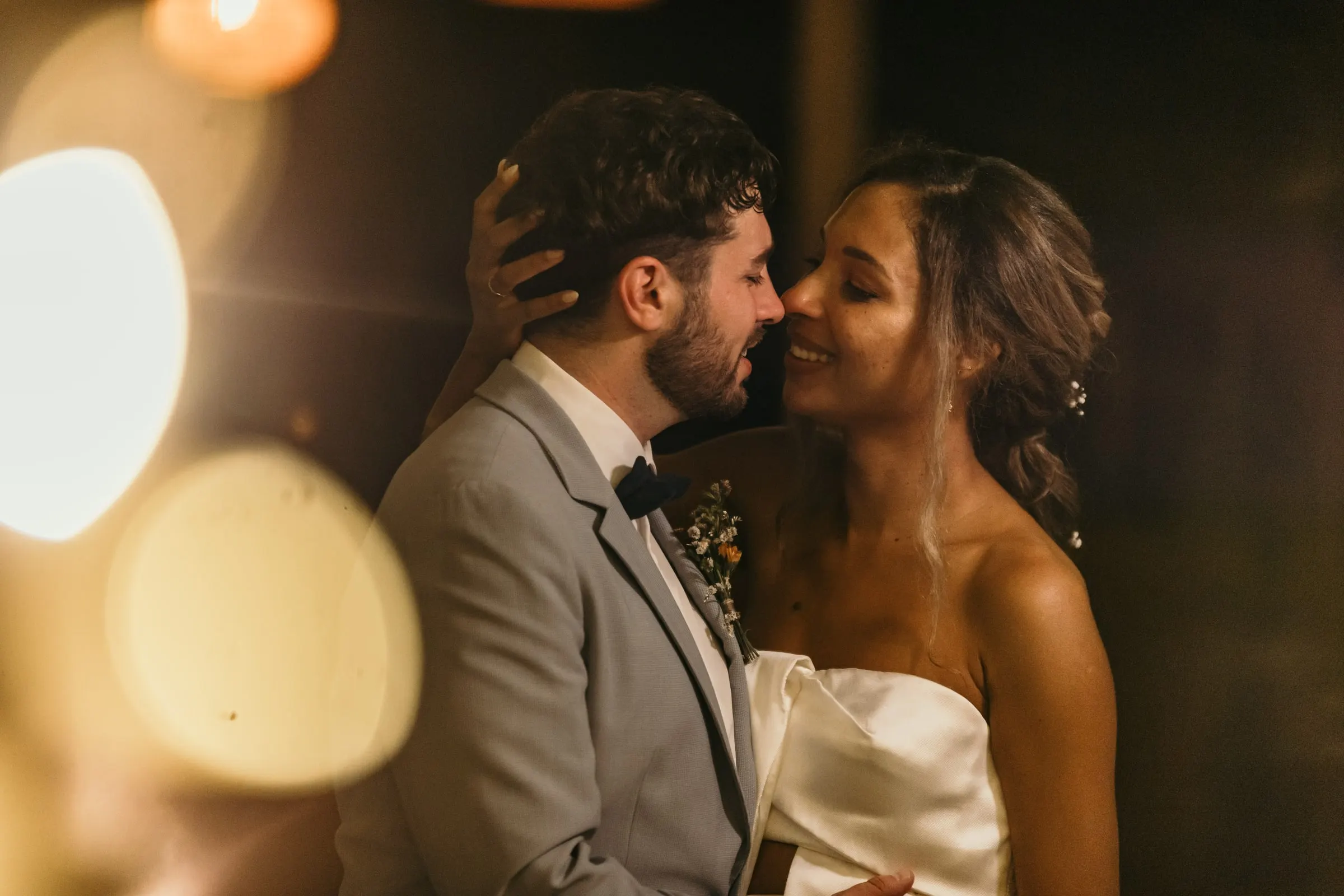 Couple almost kissing, with warm bokeh lights in the foreground