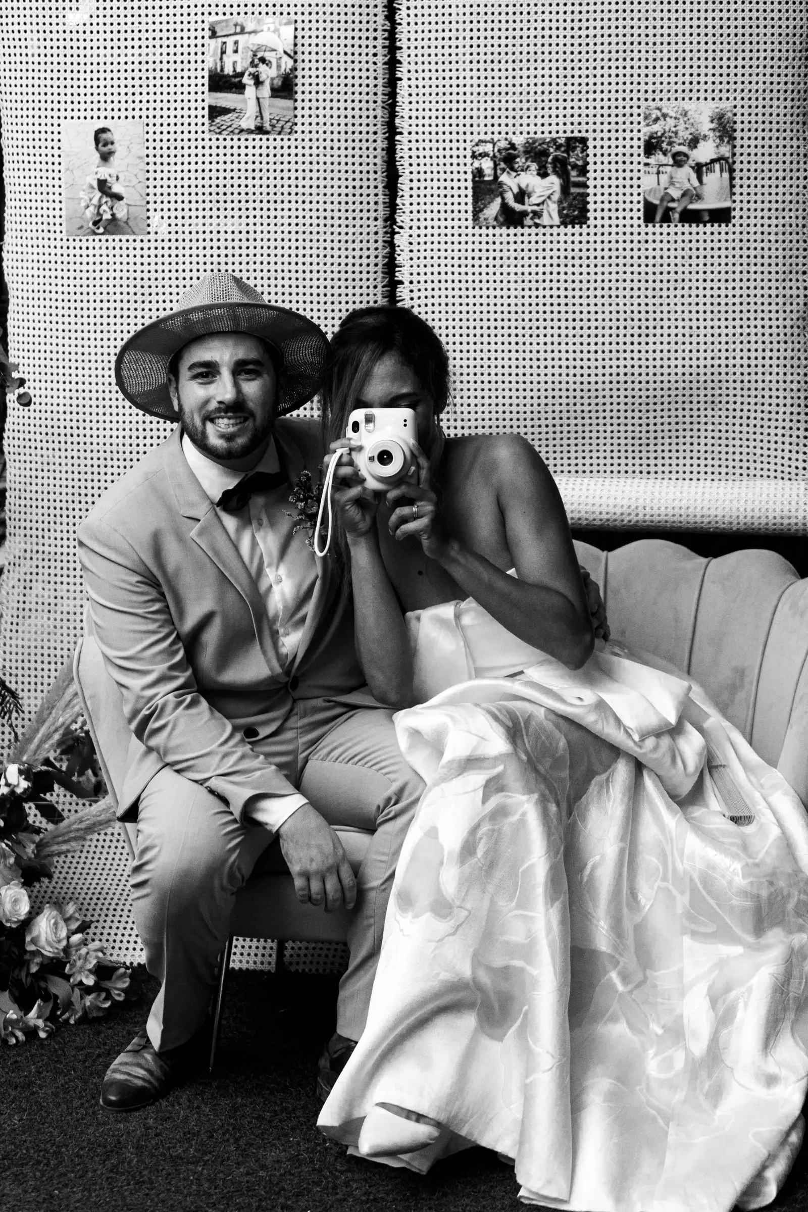 Black and white photo of the couple taking an instant photo of themselves in the photo corner