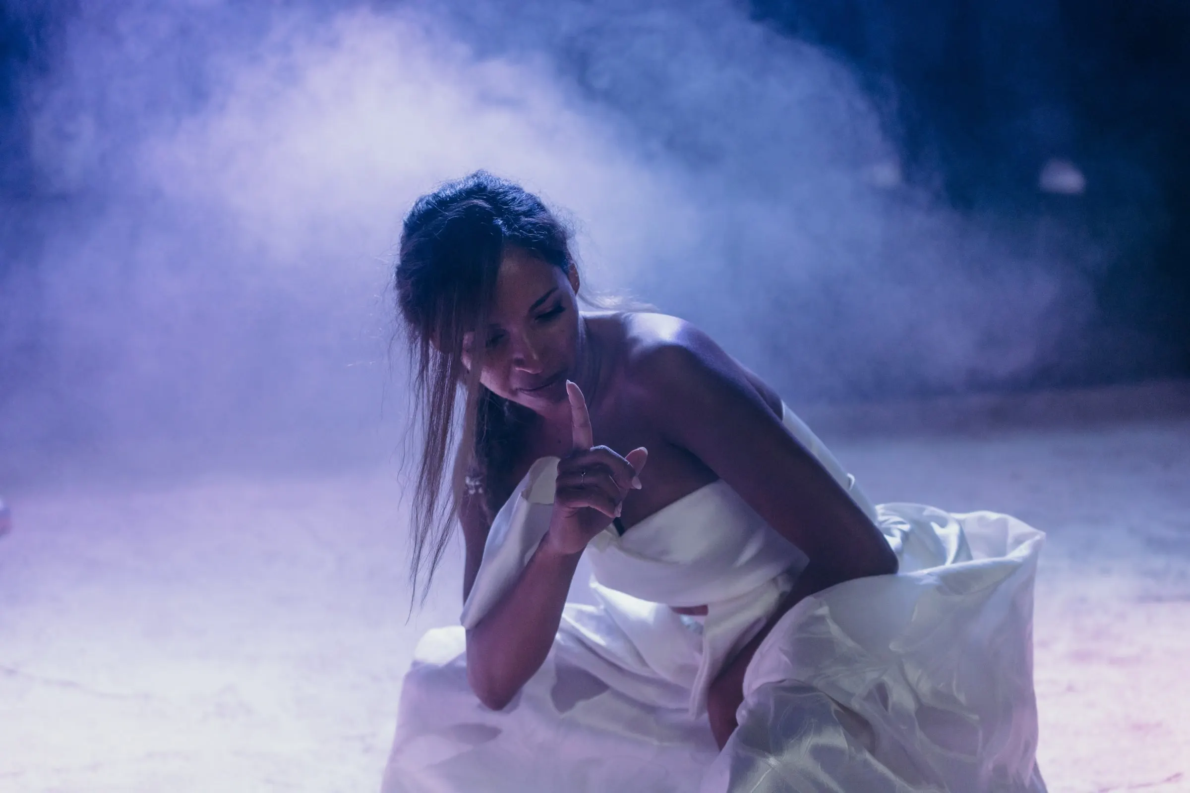 Bride dancing in a cloud of smoke under blue and violet light