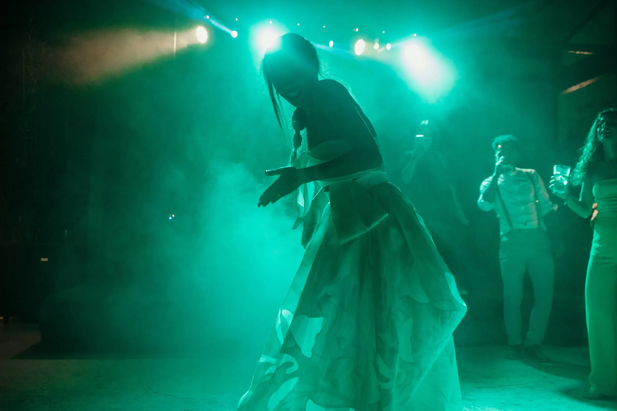 Bride's silhouette dancing in turquoise smoke and stage lights