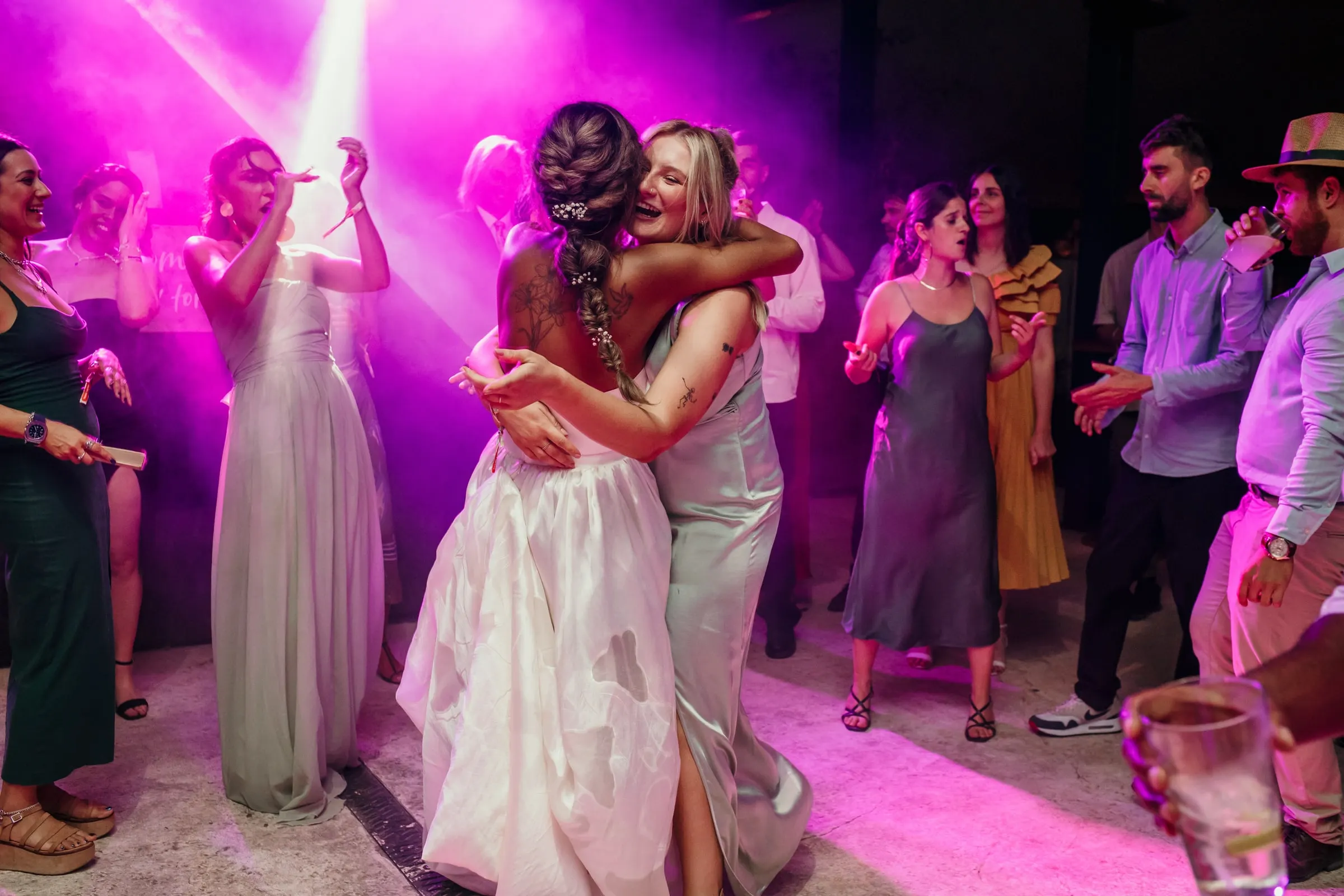 Bride hugging a friend in the middle of the dance floor