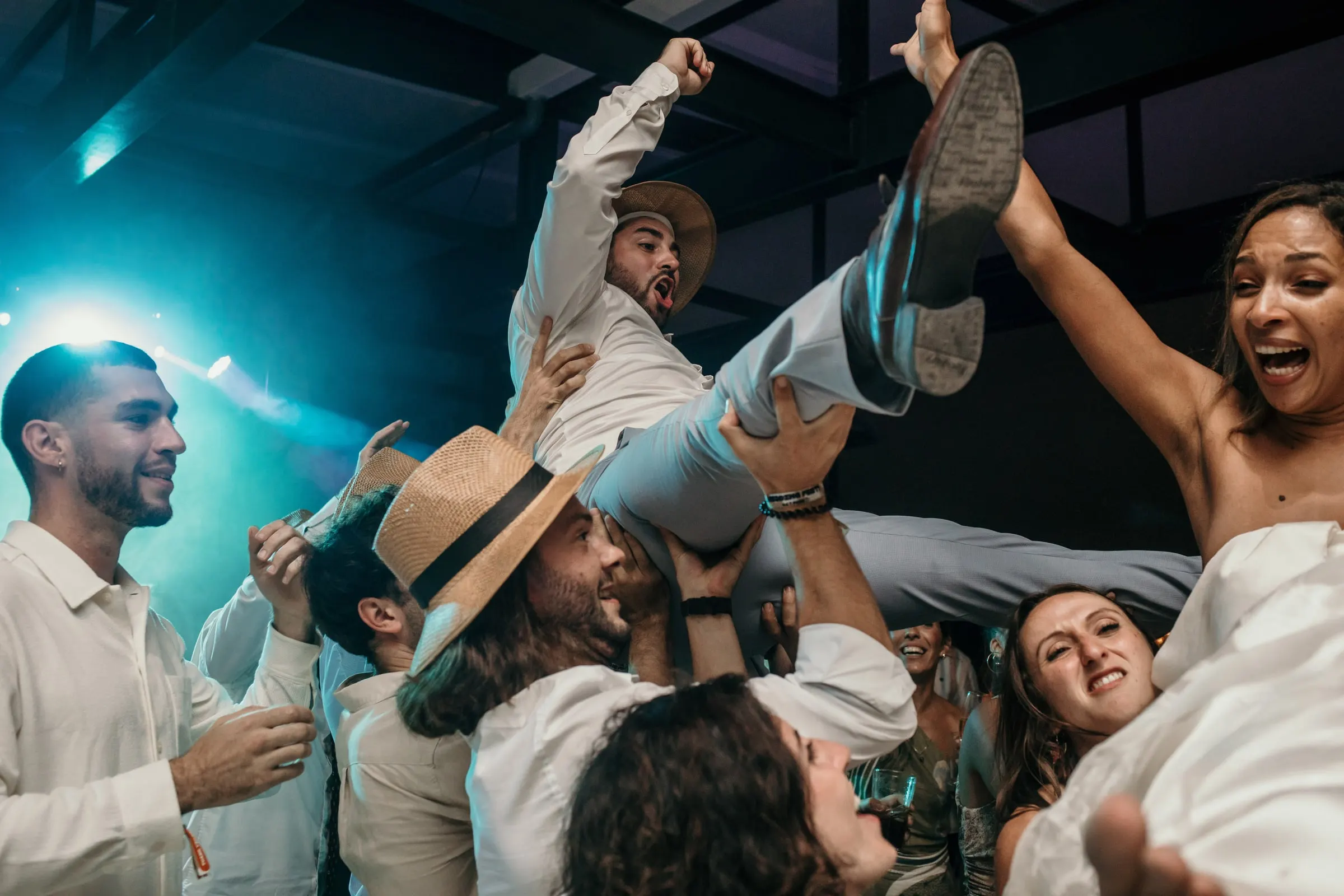 Groom thrown into the air by his friends in turquoise light