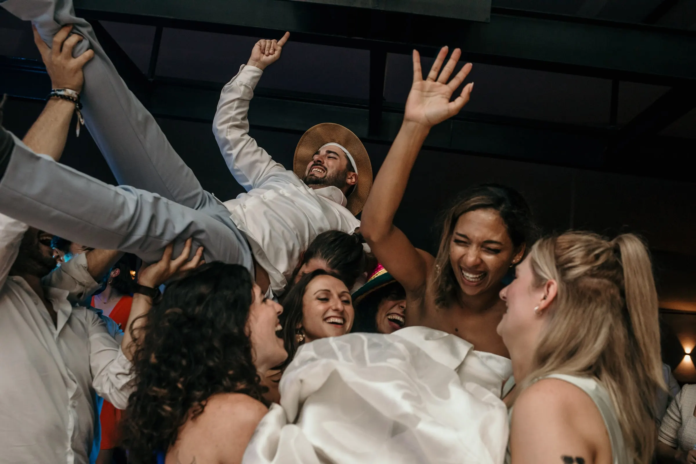 Bride and friends laughing as the groom is carried overhead
