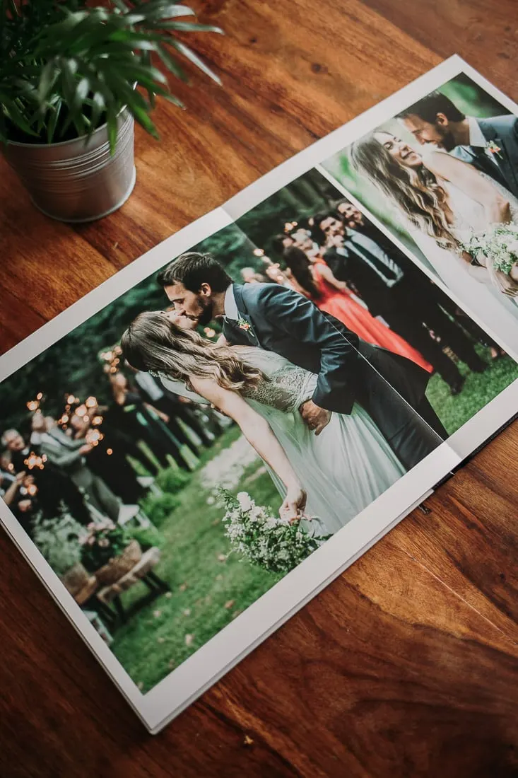 Handmade fine-art wedding album open on a wooden table, Picart