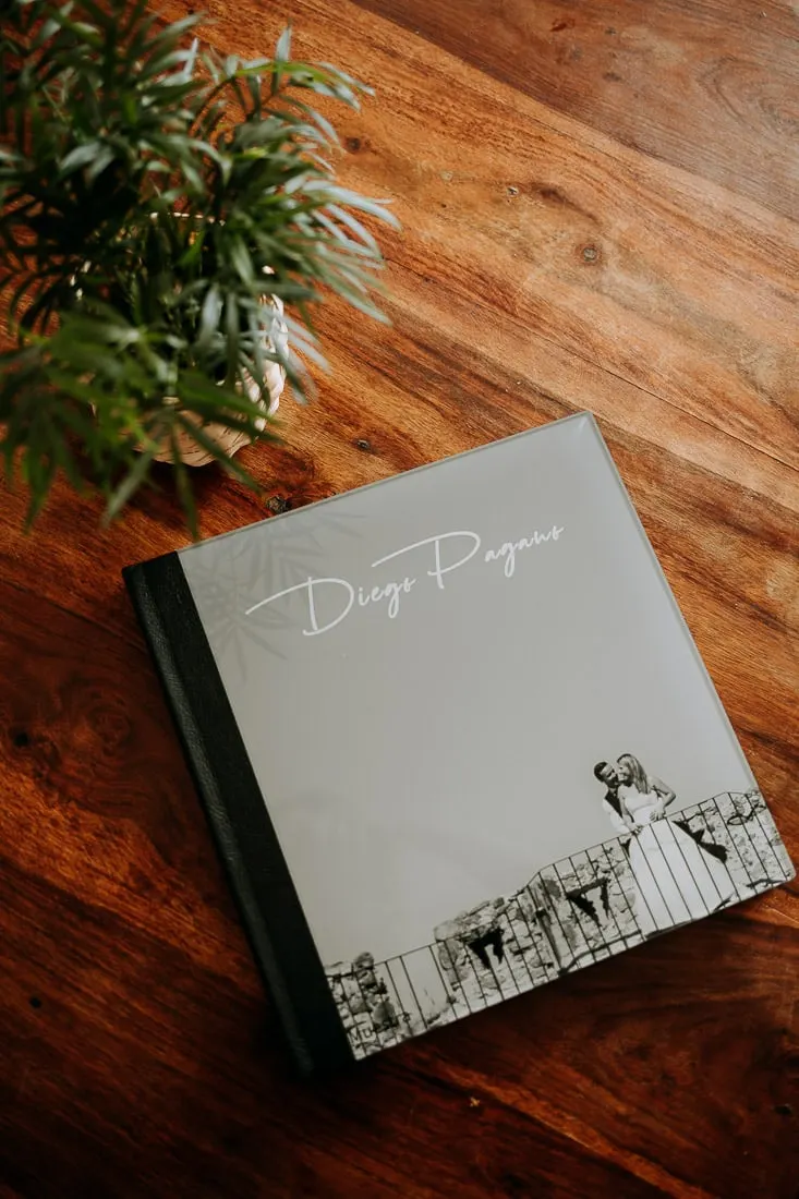 Closed fine-art wedding album with a grey cover and a printed photo, on a wooden table, Picart