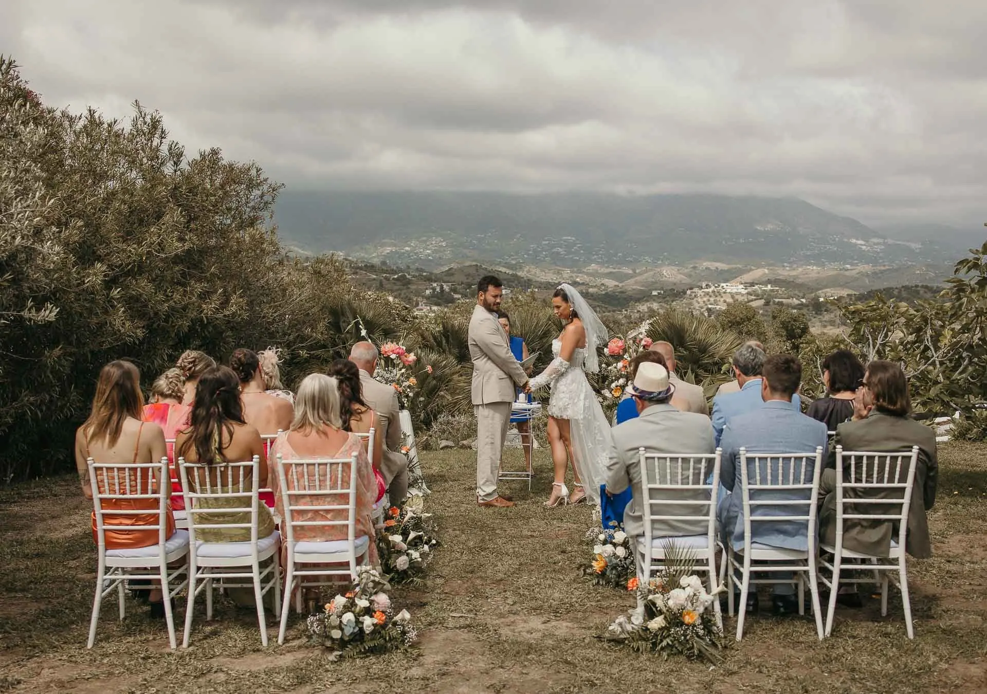Wide view of the outdoor ceremony with guests on white chairs and the valley beyond, Hacienda San José, Mijas
