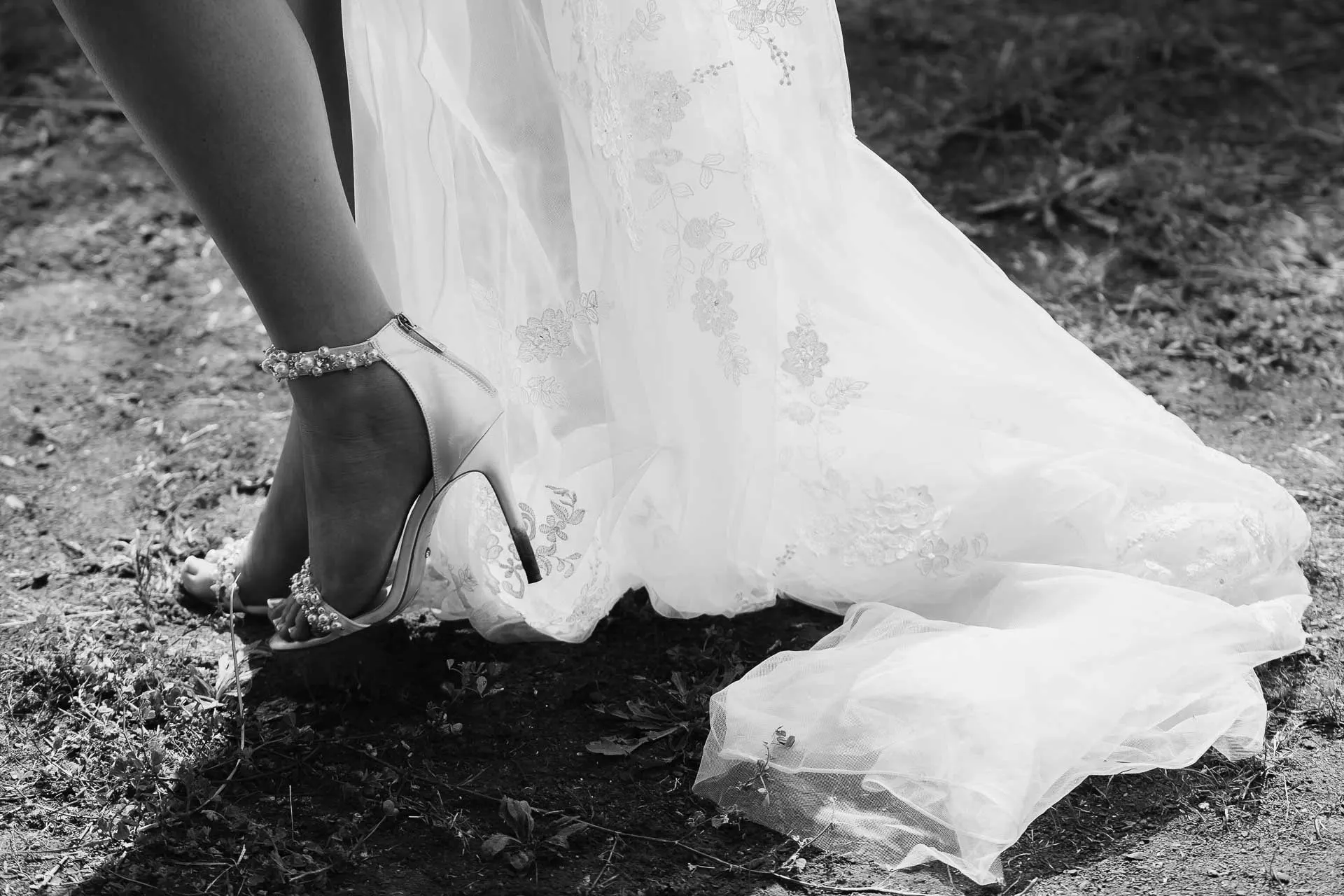 Black and white detail of the bride's pearl sandal and lace train on the grass, Hacienda San José, Mijas