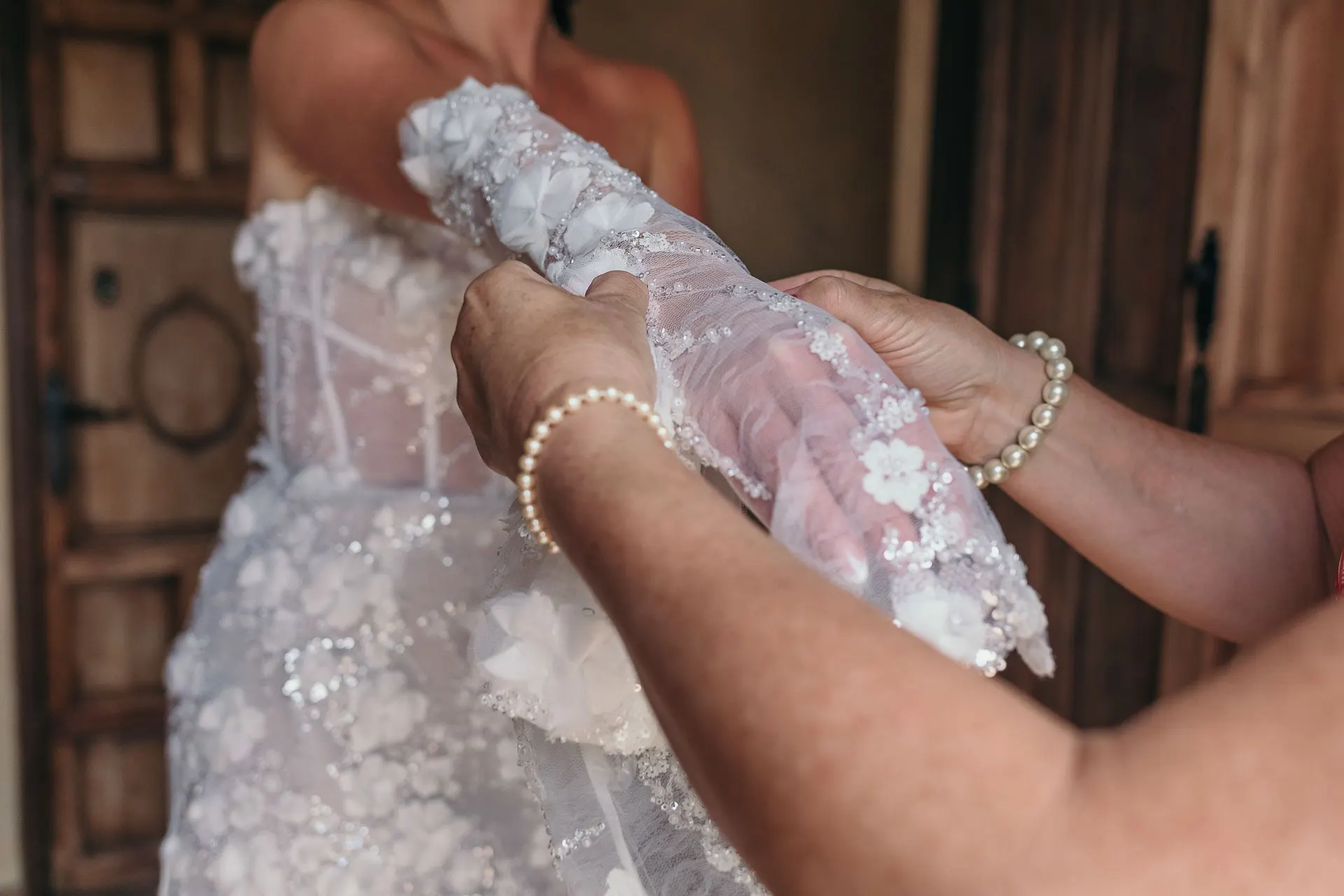 Close-up of hands helping the bride into her lace gloves, a pearl bracelet on one wrist, Hacienda San José, Mijas