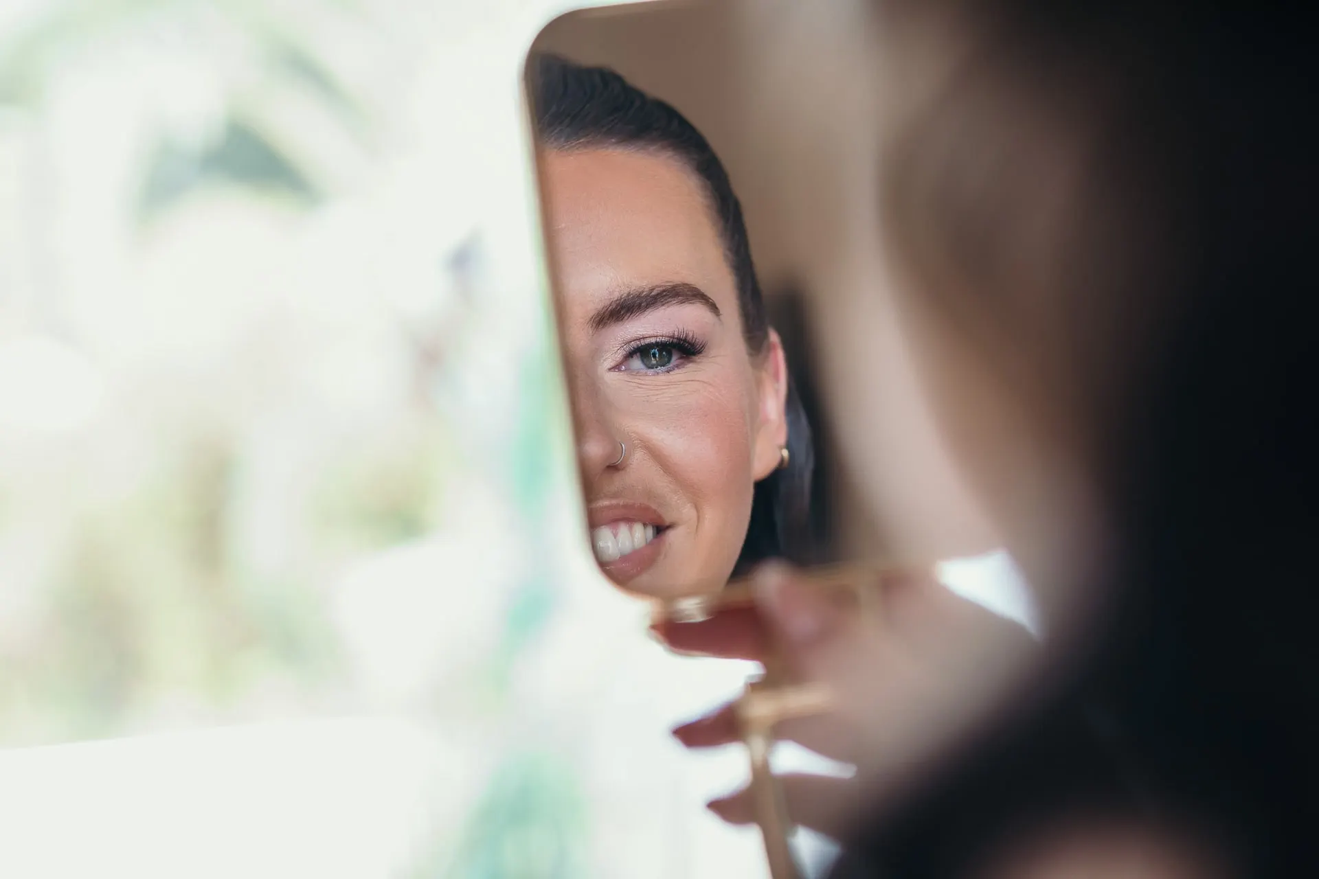 The bride's face reflected in a hand mirror as she checks her make-up, Hacienda San José, Mijas