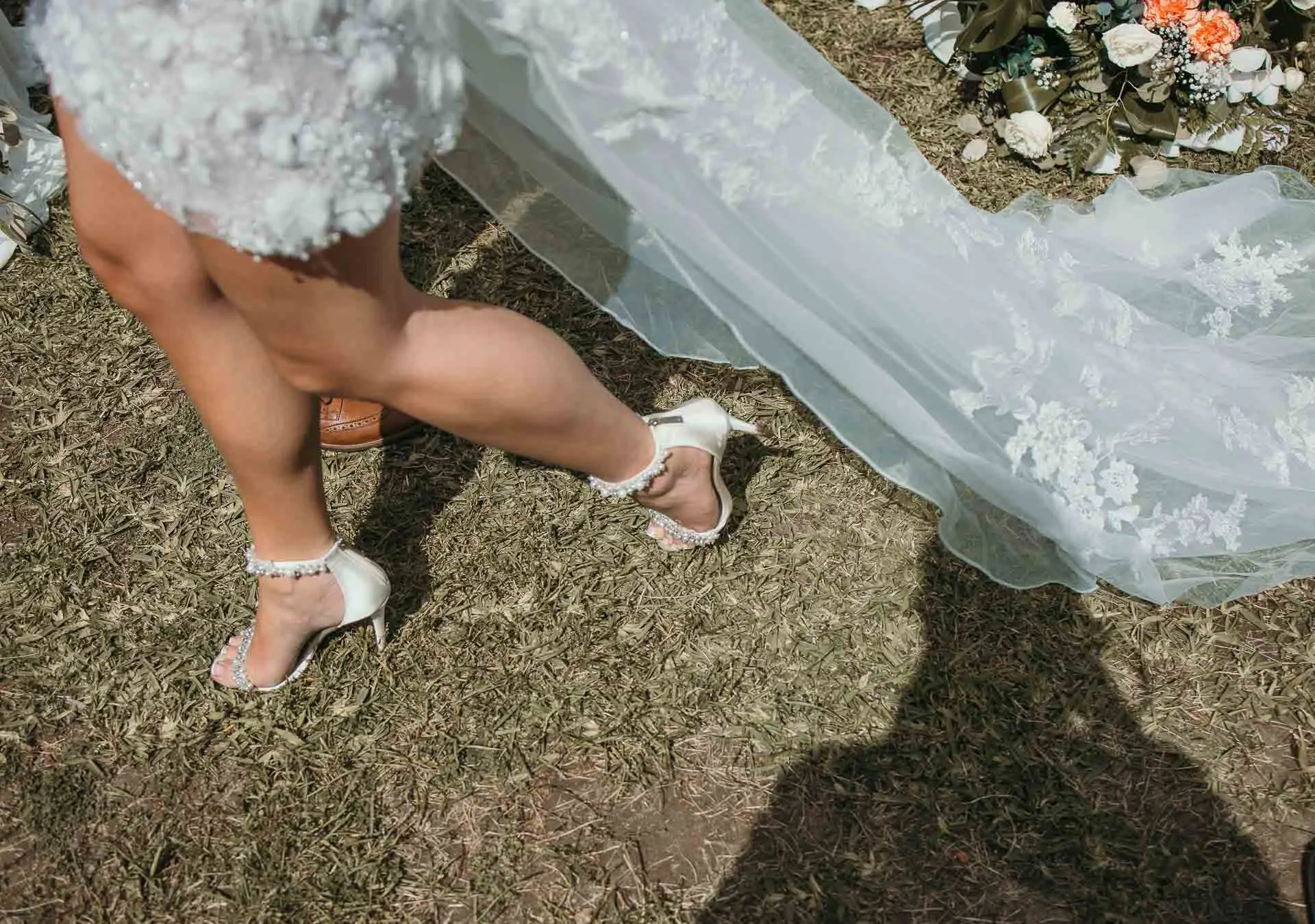 Detail of the bride's legs, pearl heels and long lace veil trailing over the grass, Hacienda San José, Mijas