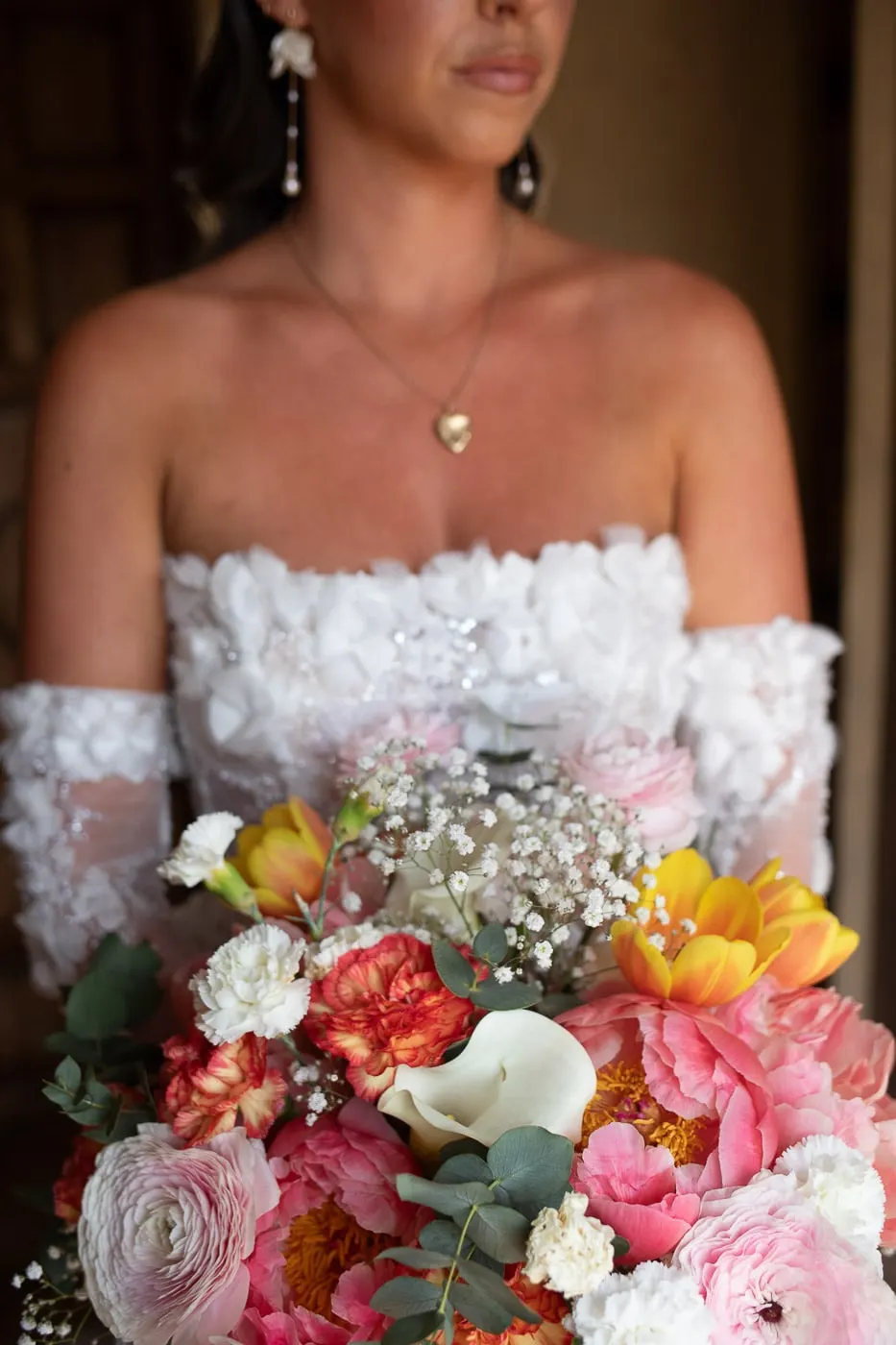 Detail of the bride's strapless floral bodice, gold locket and colourful bouquet, Hacienda San José, Mijas