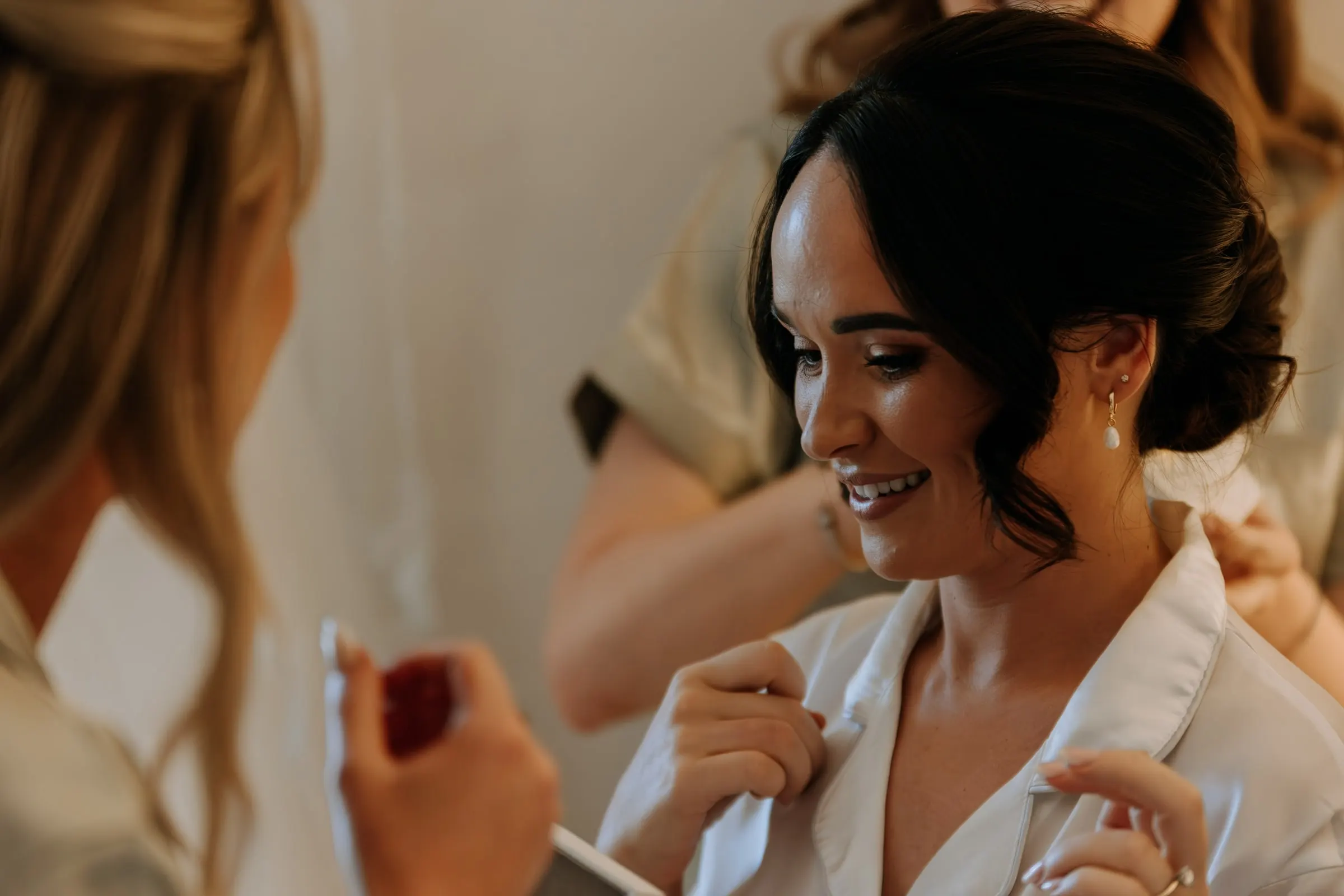 Close-up of the bride smiling as her friends help her get ready at Hacienda San José