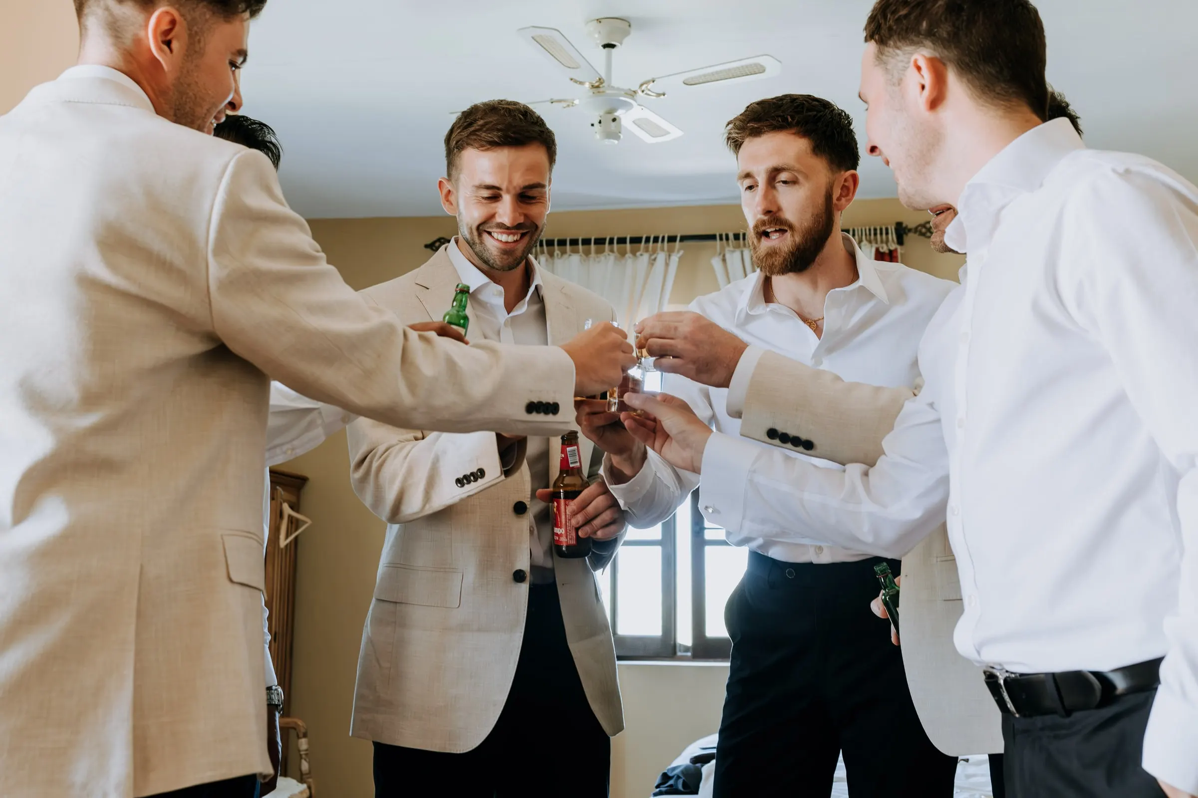 Groom and groomsmen clinking glasses of spirits before the wedding at Hacienda San José
