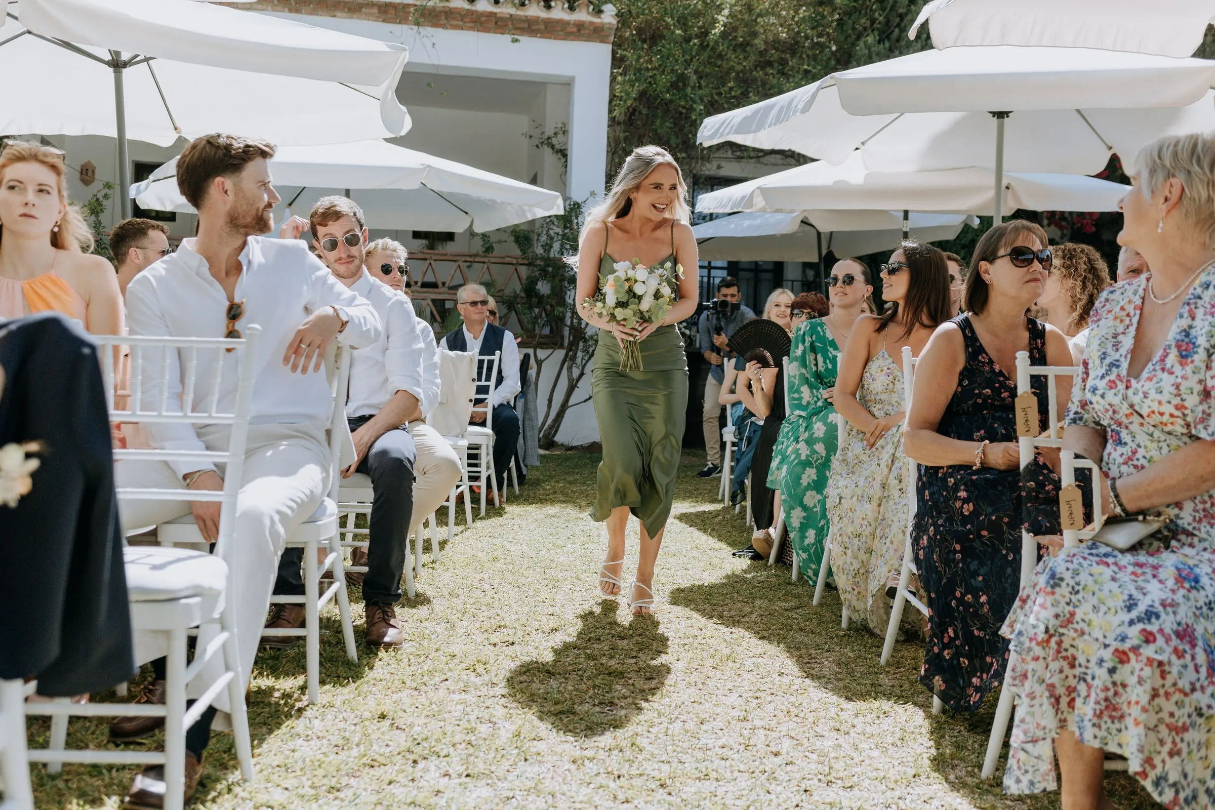 Bridesmaid with her bouquet between rows of white chairs, garden ceremony in Mijas