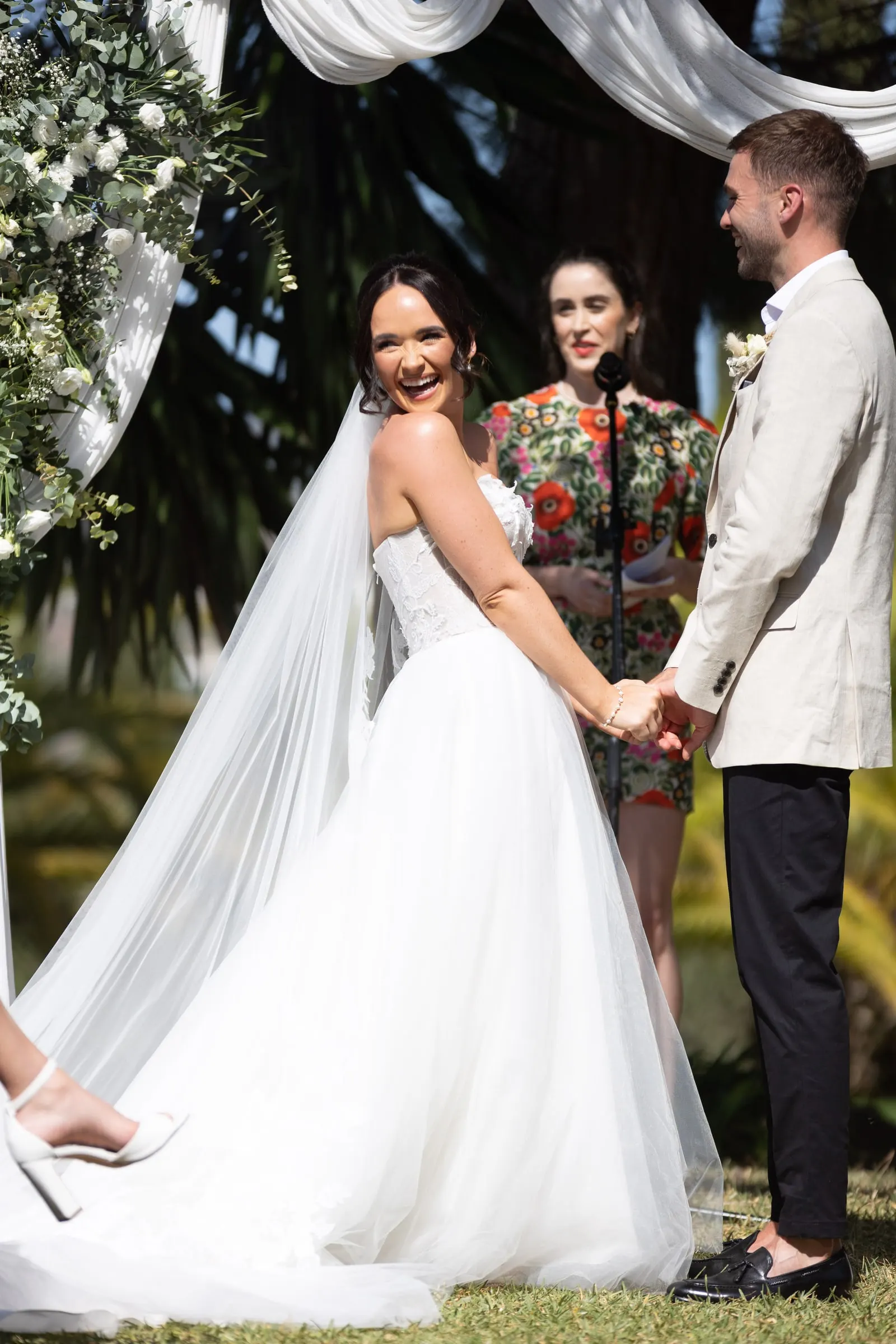 Bride laughing as she holds the groom's hands under the draped arch, Hacienda San José