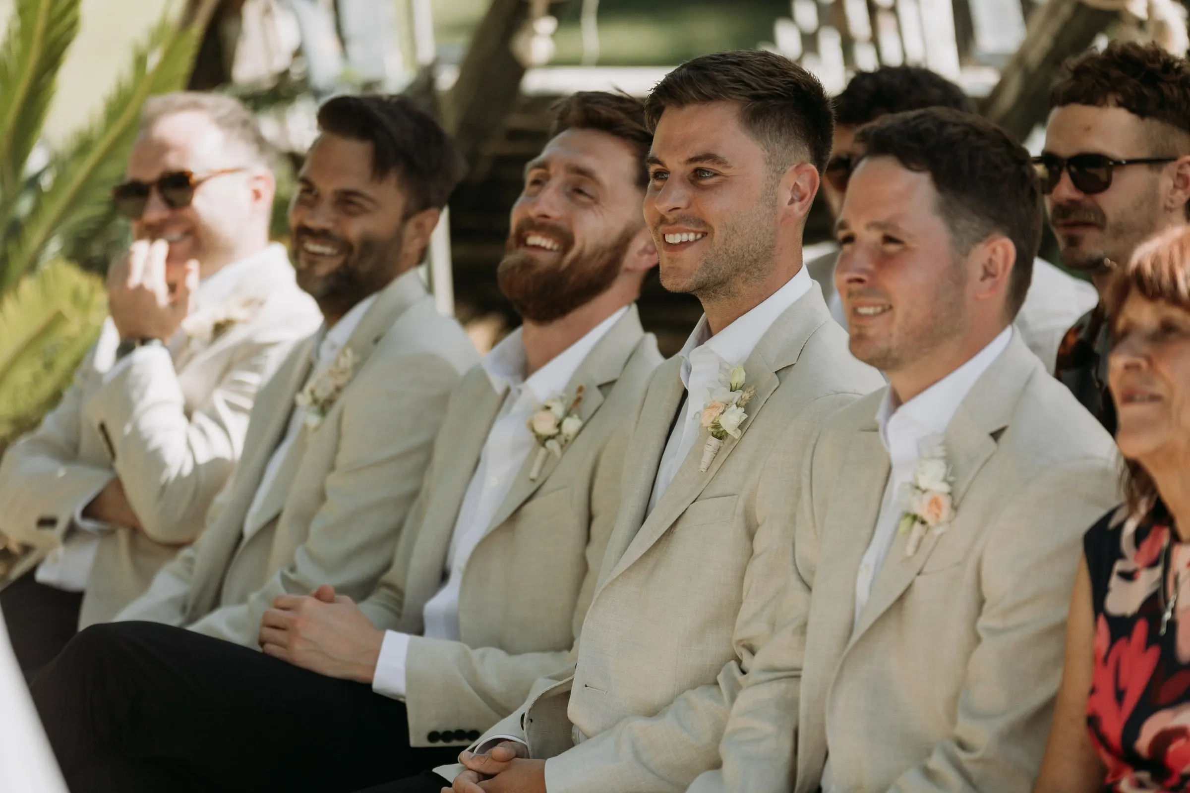 Groomsmen in beige jackets laughing during the ceremony at Hacienda San José