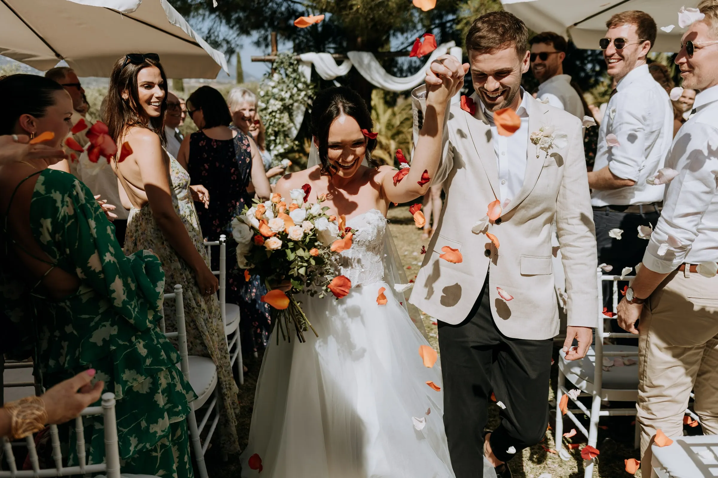 Newlyweds walking back up the aisle through orange and white petals, Hacienda San José
