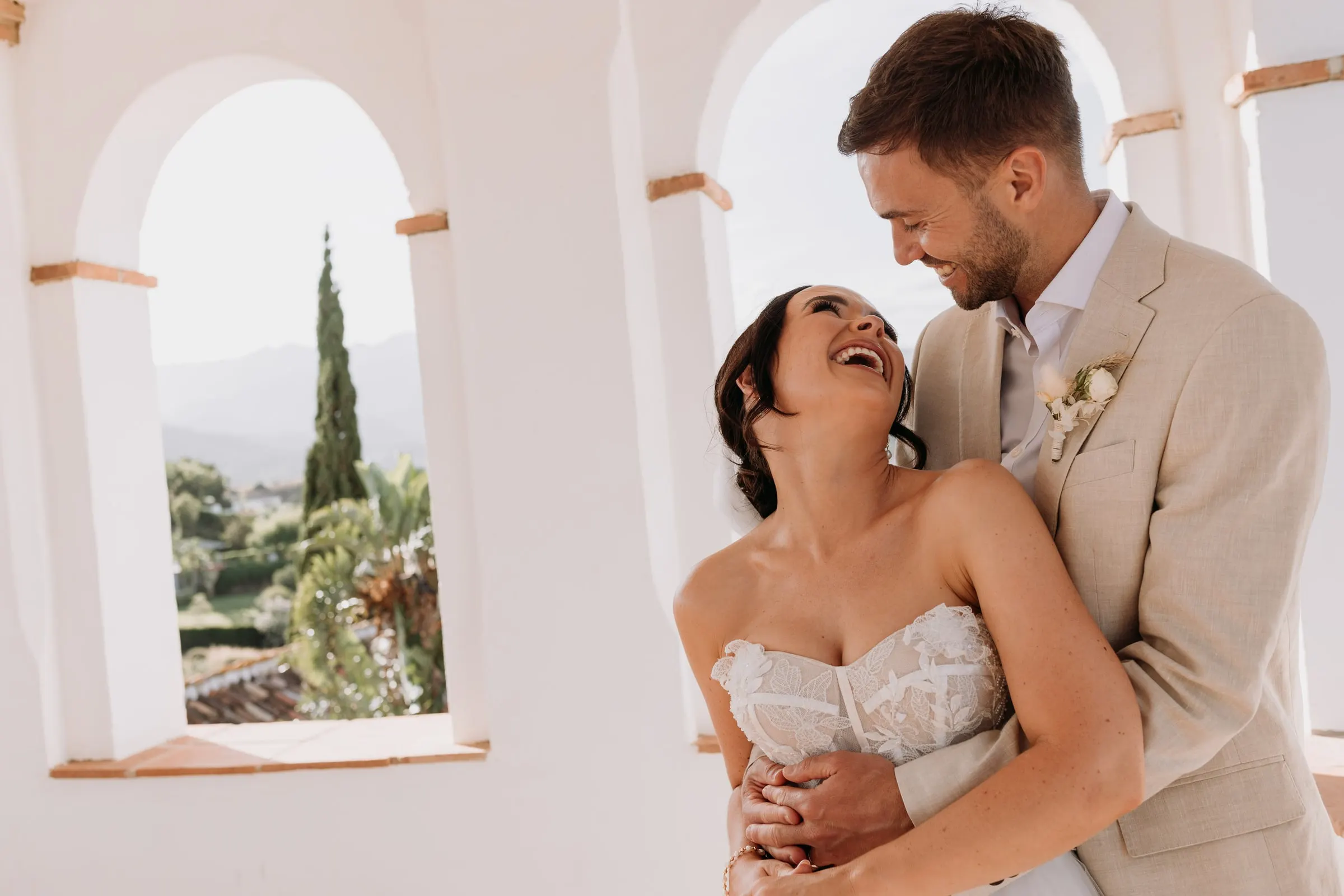 Bride throwing her head back with laughter in the groom's arms, tower of Hacienda San José