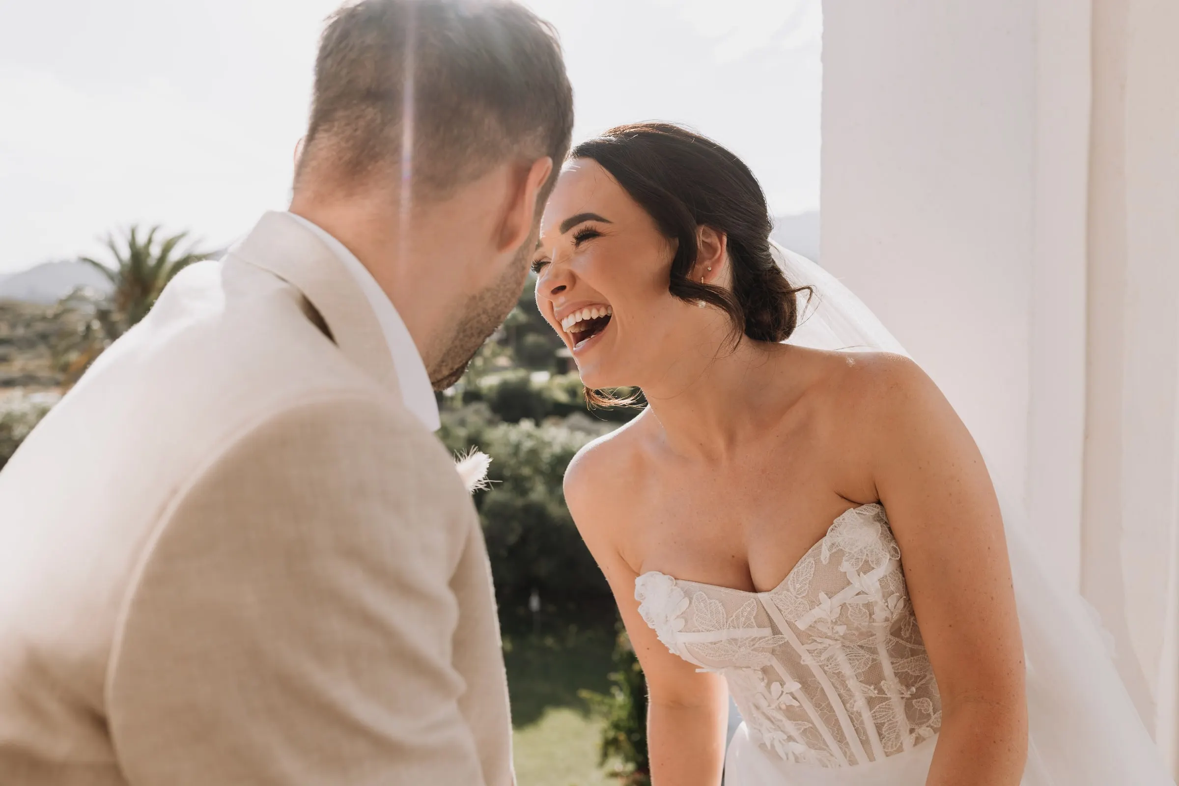 Bride laughing at the groom in the tower, with the hills of Mijas behind