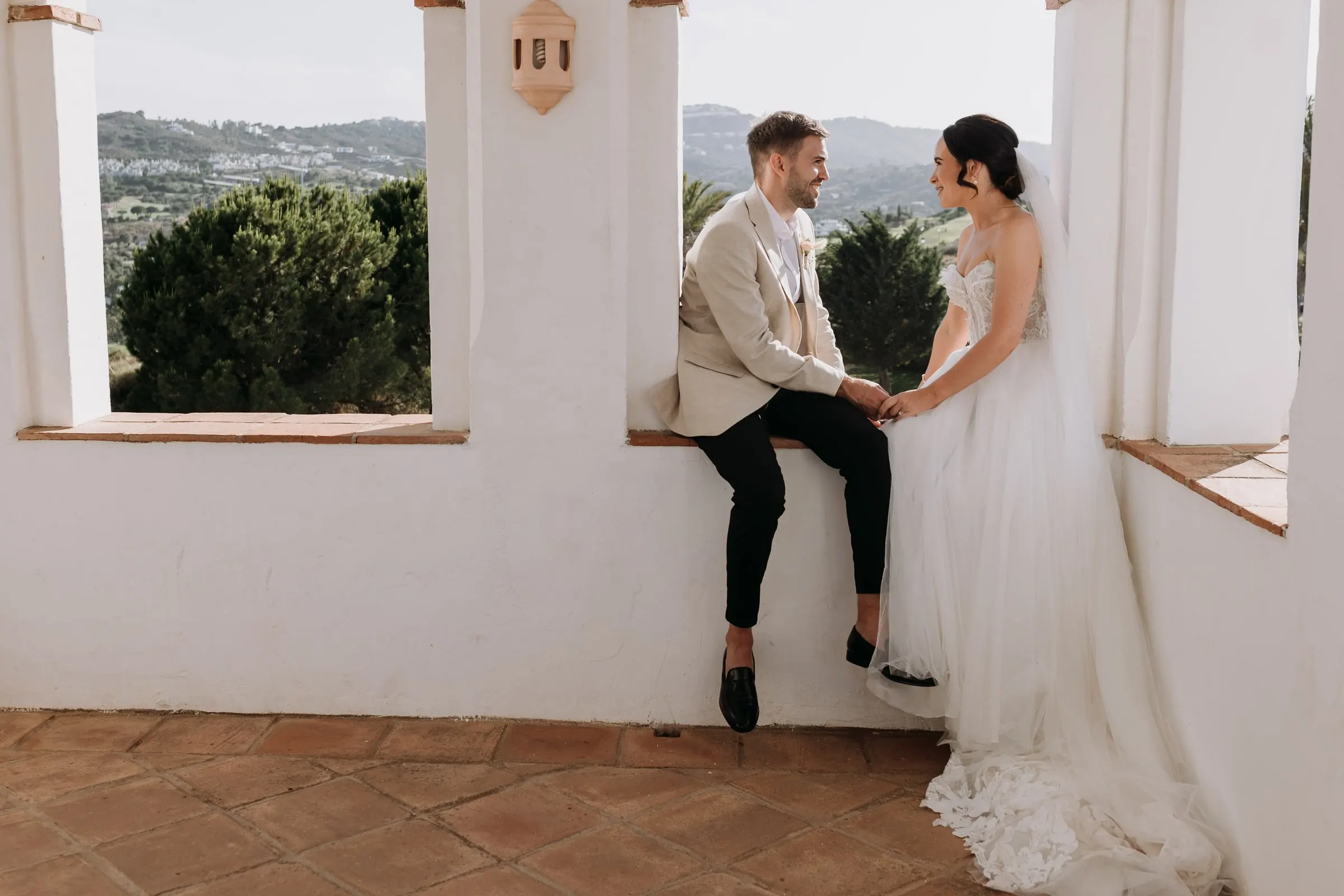 Bride and groom holding hands at the open arch of the tower above the Mijas valley
