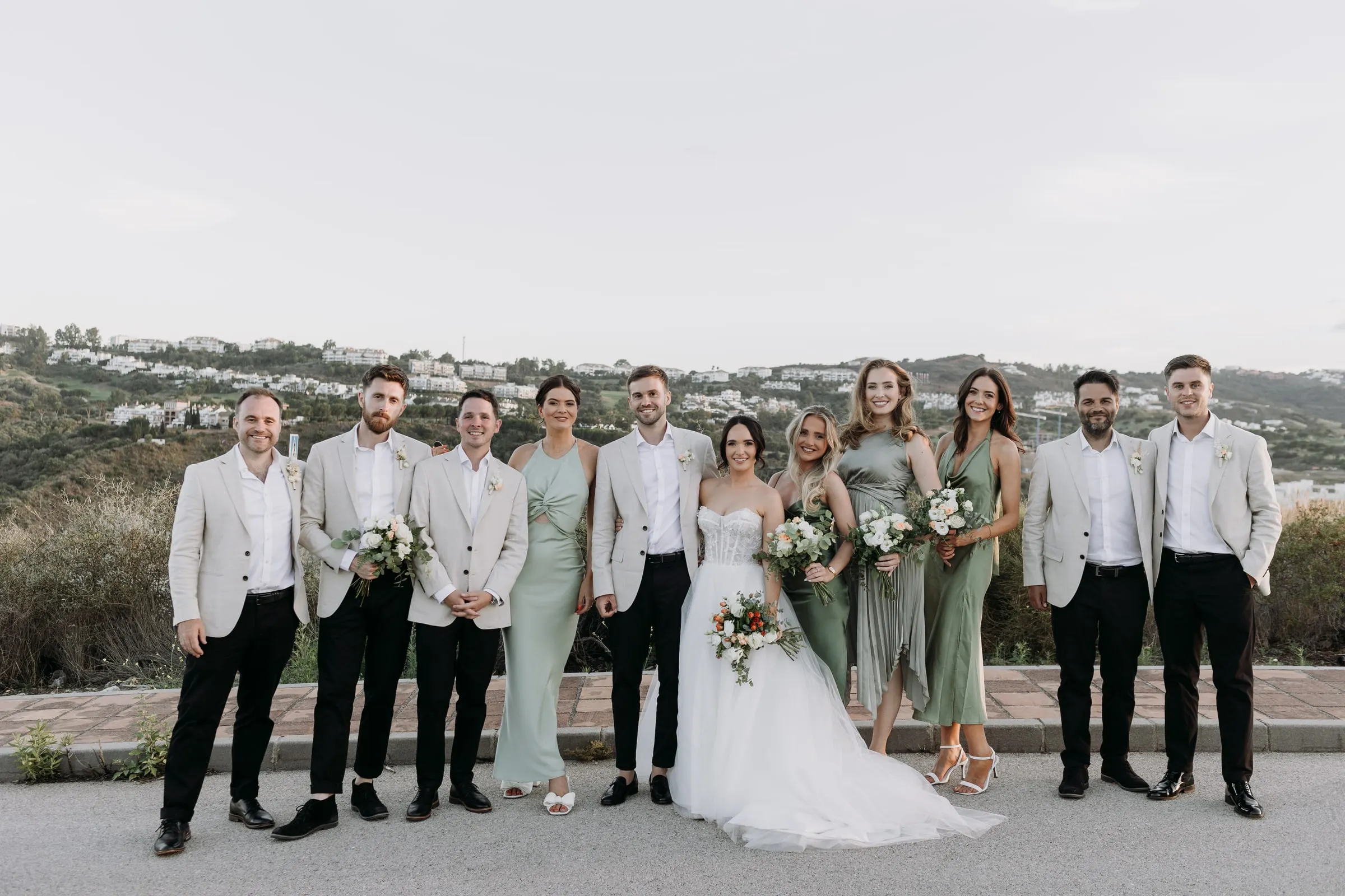 Bride and groom with the whole bridal party on the road above the coast, Mijas
